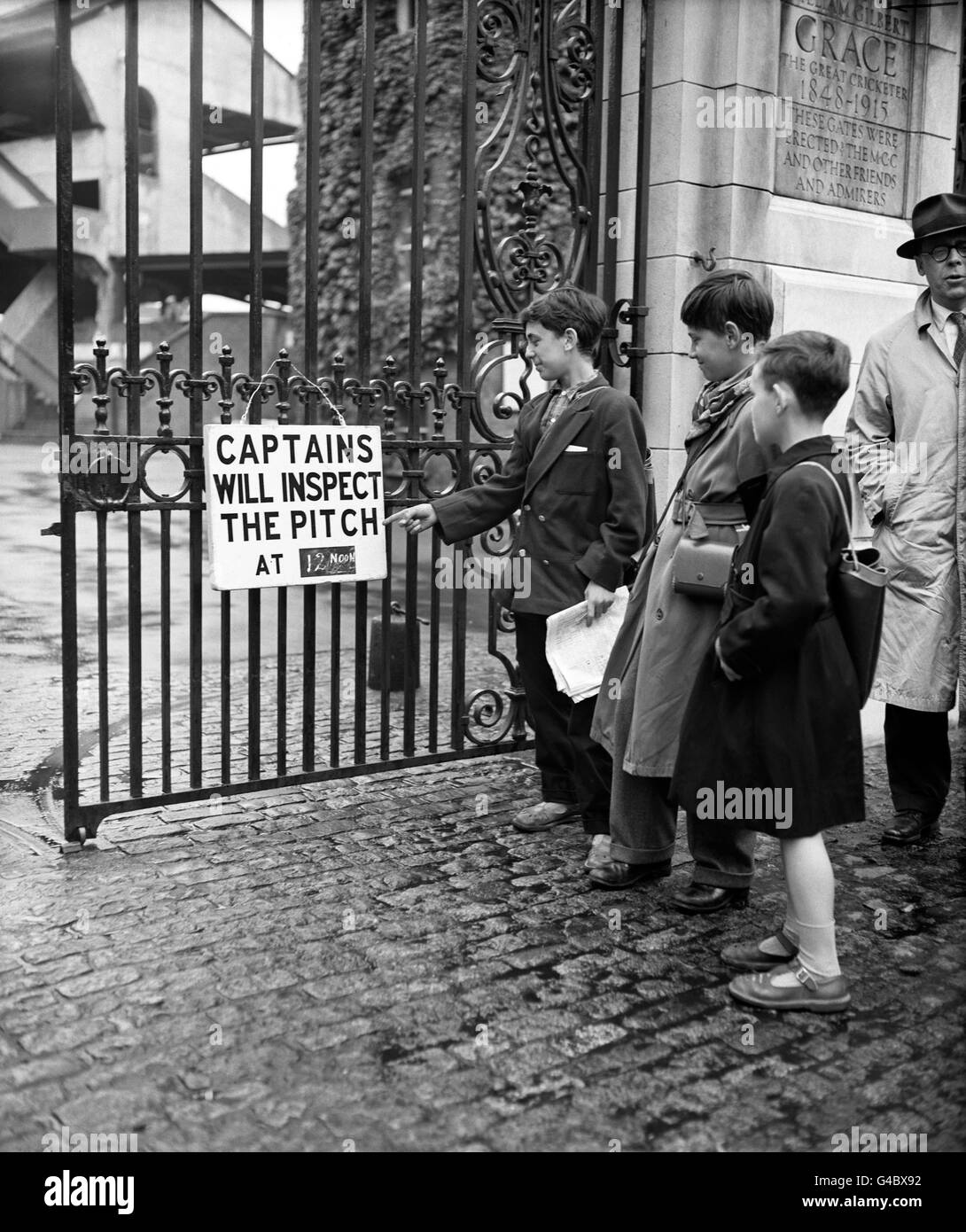 Cricket - County Championship - Middlesex CCC v Yorkshire CCC - Day One - Lord's. Young fans outside Lord's reading the sign saying 'Captains will insect the pitch at 12 noon' as rain delays the start of play on Day 1. Stock Photo