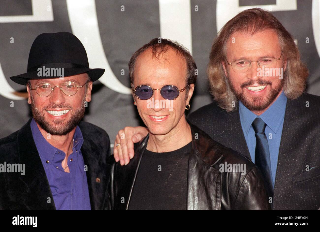 The Bee Gess (from left) Maurice, Robin and Barry Gibb pose for the media during a photocall at London's Cafe Royal where they unveiled plans for a leisurely world tour, 31 years after their first hit. 27/9/99 to be honoured with a collection of stamps which are to be issued by the island of their birth where their mother once ran a Post Office. I ve Gotta Get A Message To You is aptly one of the global hits commemorated on the set of Isle Of Man stamps to be issued on October 12. All but the youngest musical brother Andy were born on the Isle of Man, and eldest brother Barry was nine by the Stock Photo