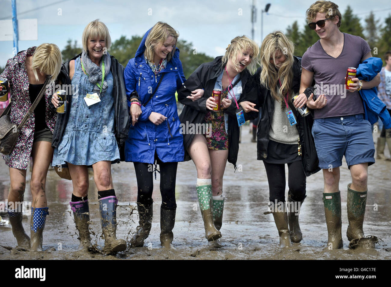 Friends from Torquay splash in the mud at the Glastonbury Festival in Somerset. Stock Photo