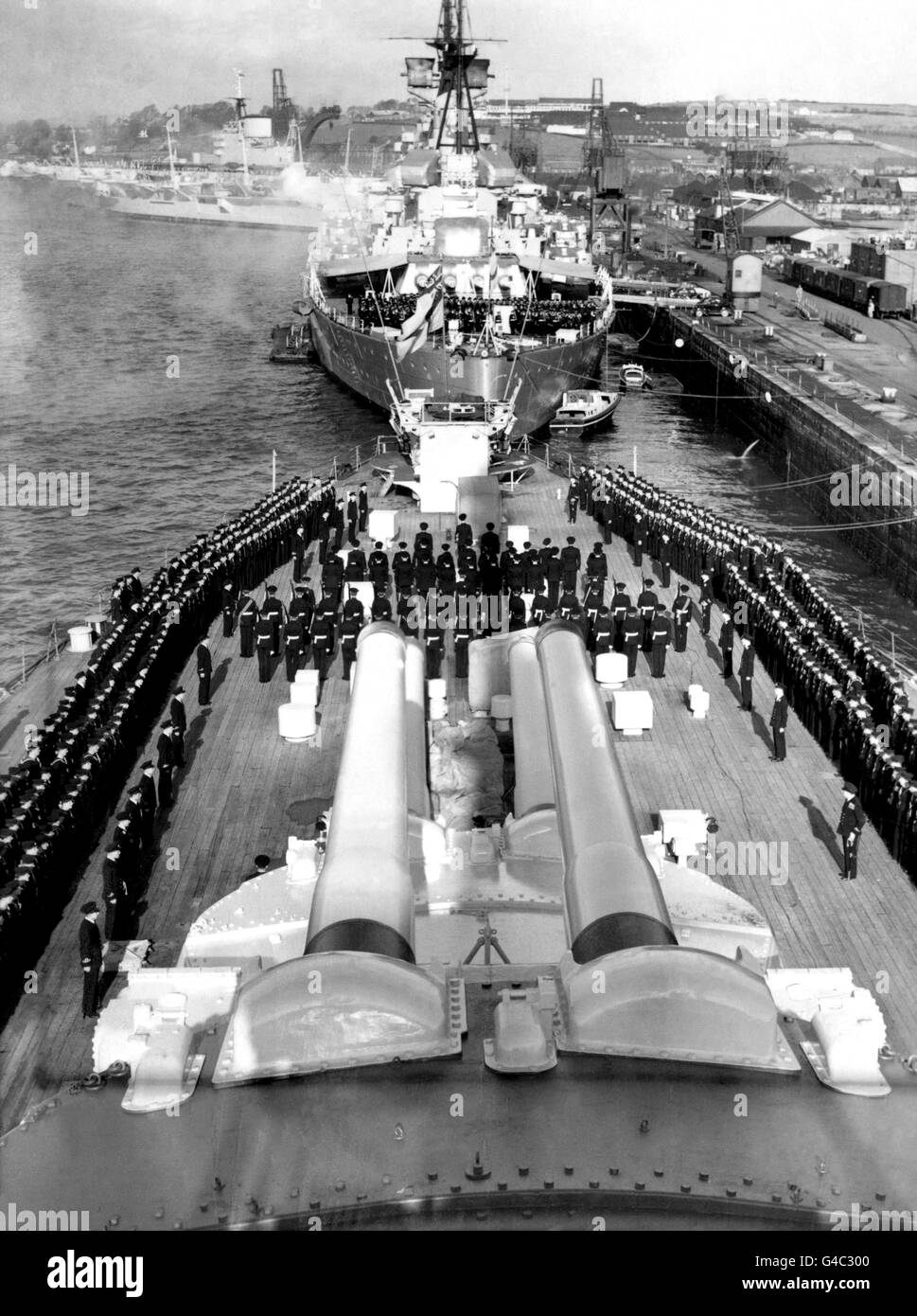 The accession of Queen Elizabeth II proclaimed on board HMS Vanguard at Devonport. In the background a similar ceremony is seen taking place on HMS Howe. Stock Photo