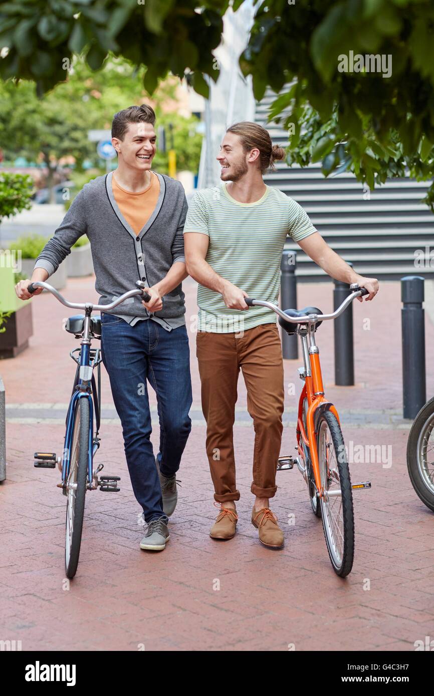 MODEL RELEASED. Two young men pushing bicycles. Stock Photo