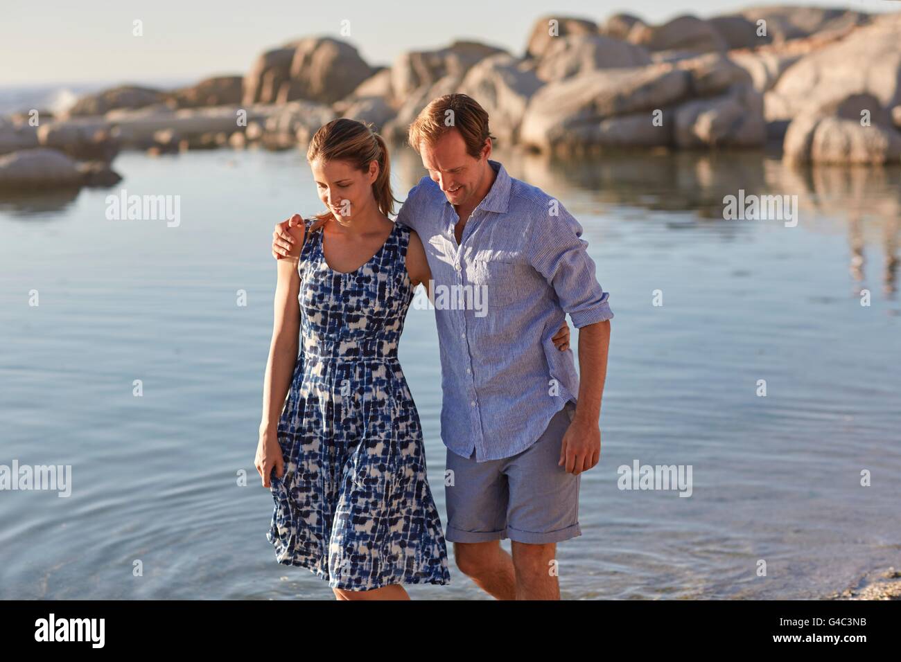 MODEL RELEASED. Couple paddling in the sea, man with arm around woman. Stock Photo