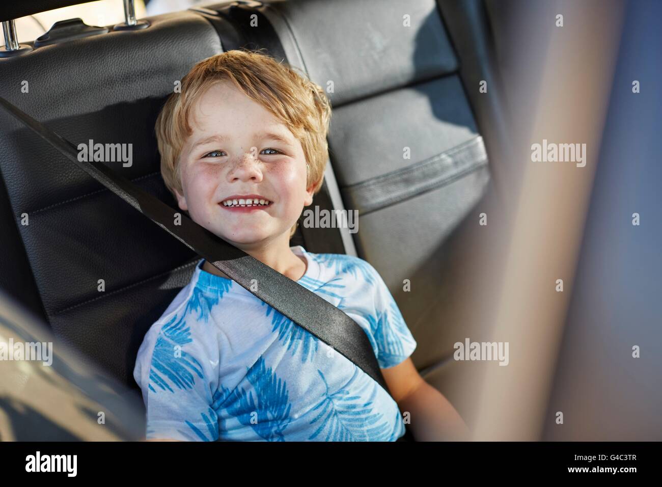 MODEL RELEASED. Young boy wearing seat belt in the back of the car. Stock Photo