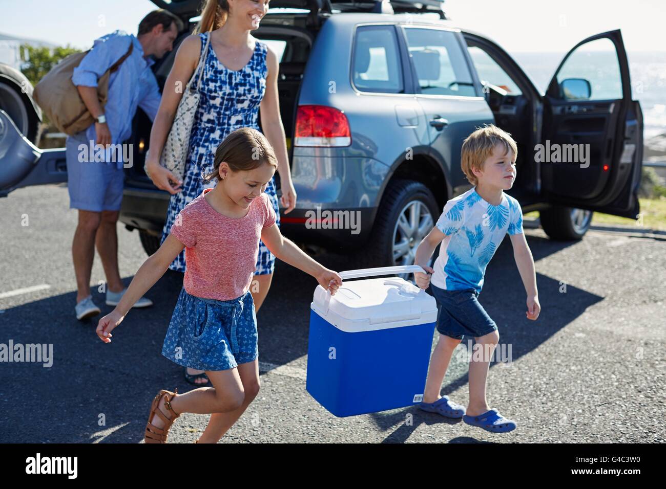 MODEL RELEASED. Family with two children carrying picnic cold box. Stock Photo