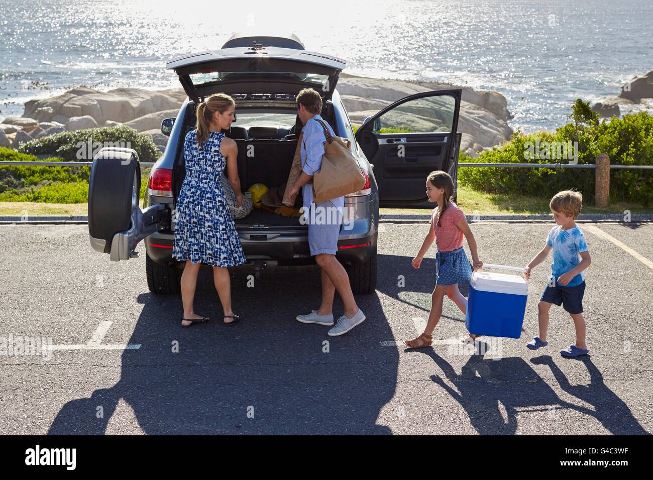 MODEL RELEASED. Family with two children unpacking the car by the beach. Stock Photo