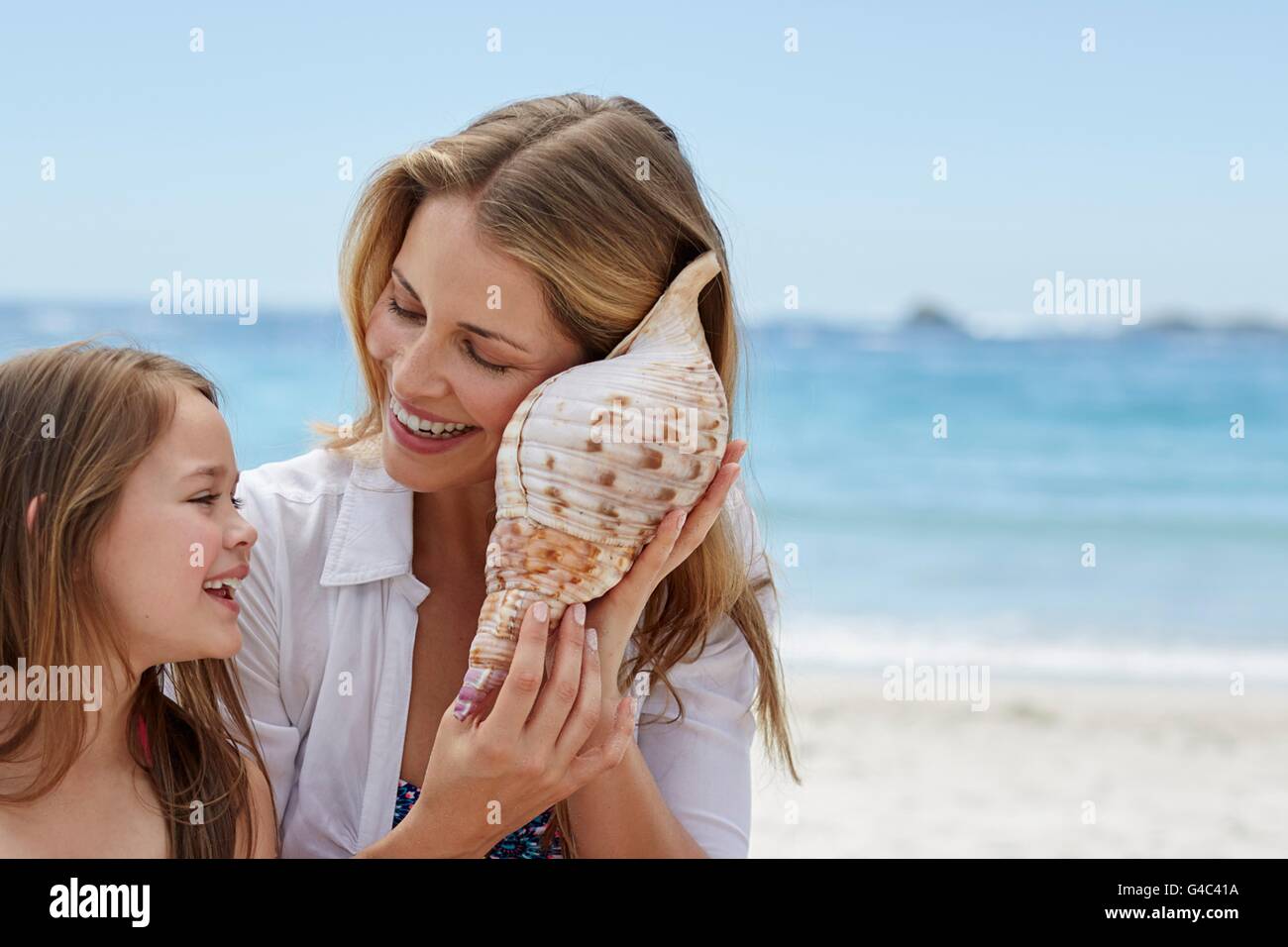 MODEL RELEASED. Mother and daughter listening to a seashell. Stock Photo