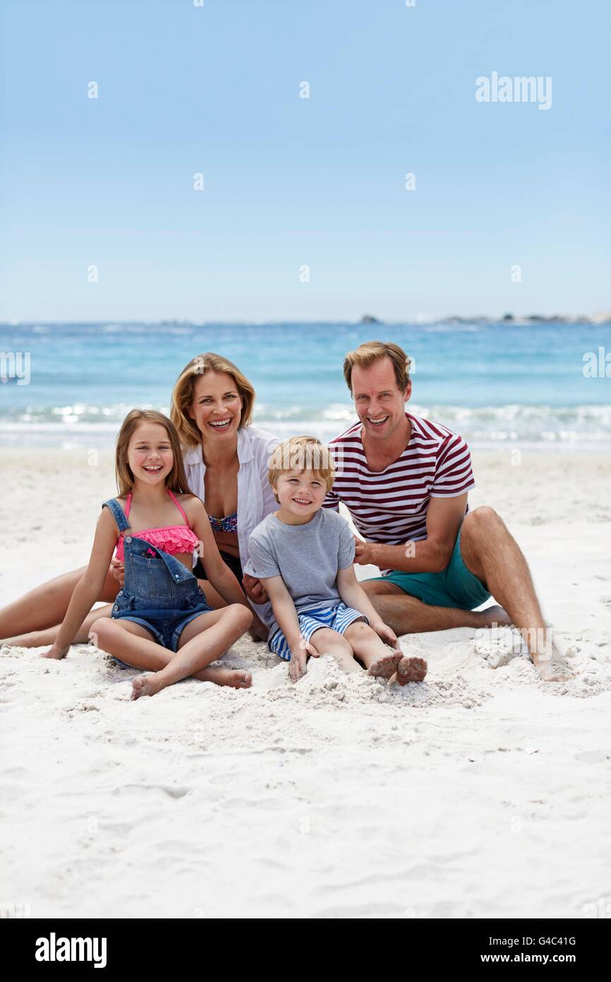 MODEL RELEASED. Family with two children sitting on the beach, portrait. Stock Photo