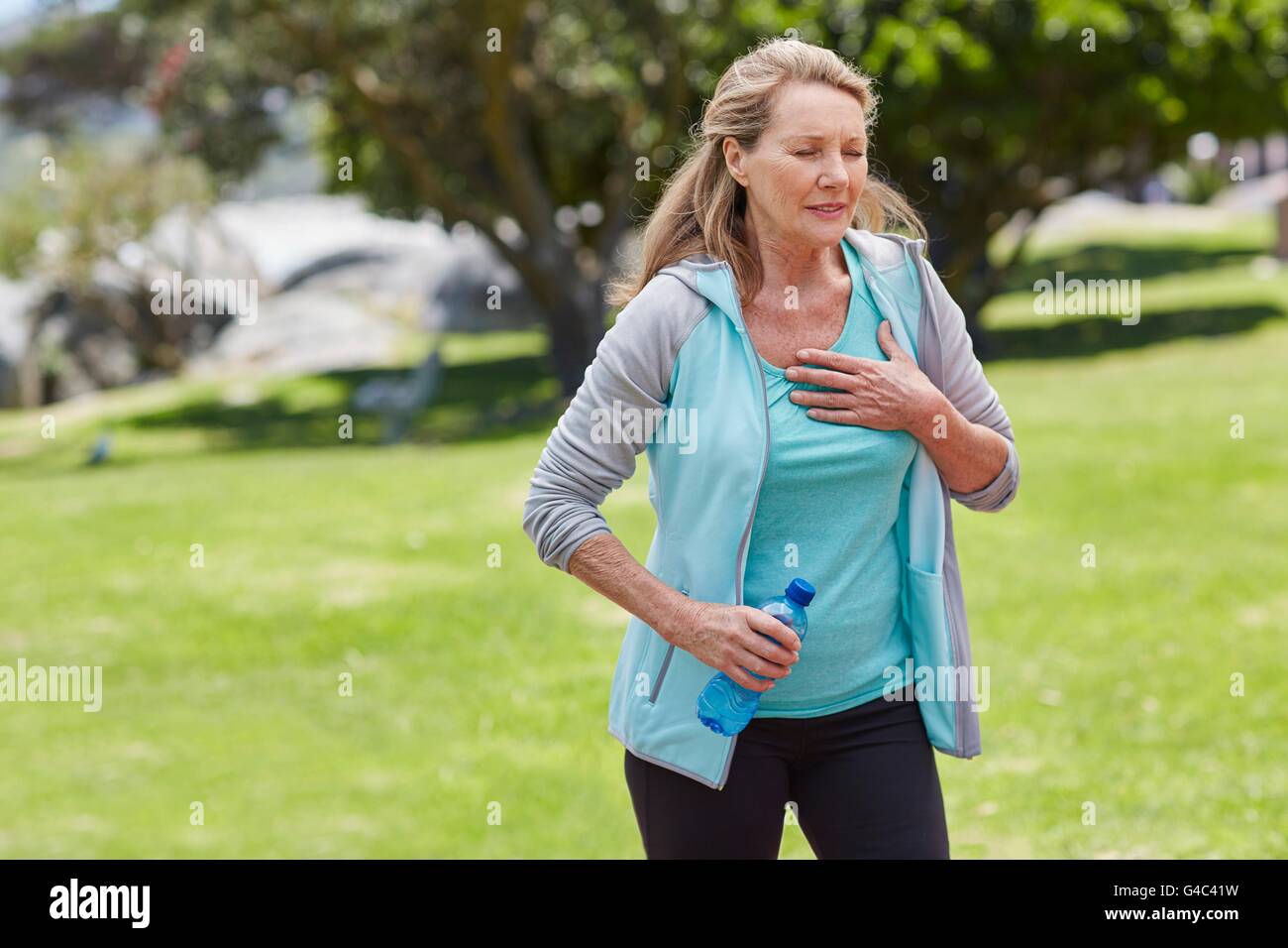 MODEL RELEASED. Senior woman exercising, holding her chest in pain. Stock Photo