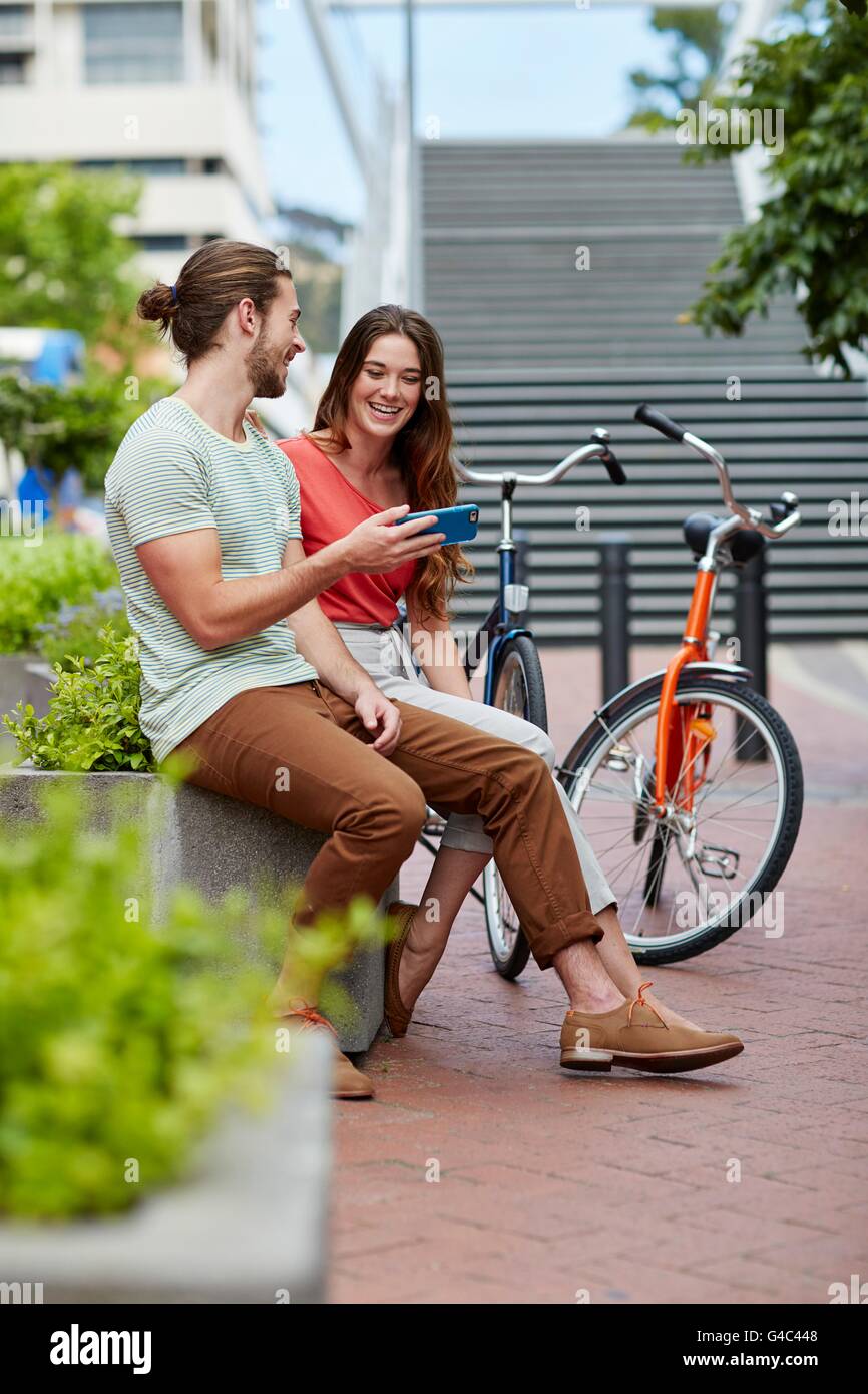 MODEL RELEASED. Young couple sitting on wall with bikes. Stock Photo