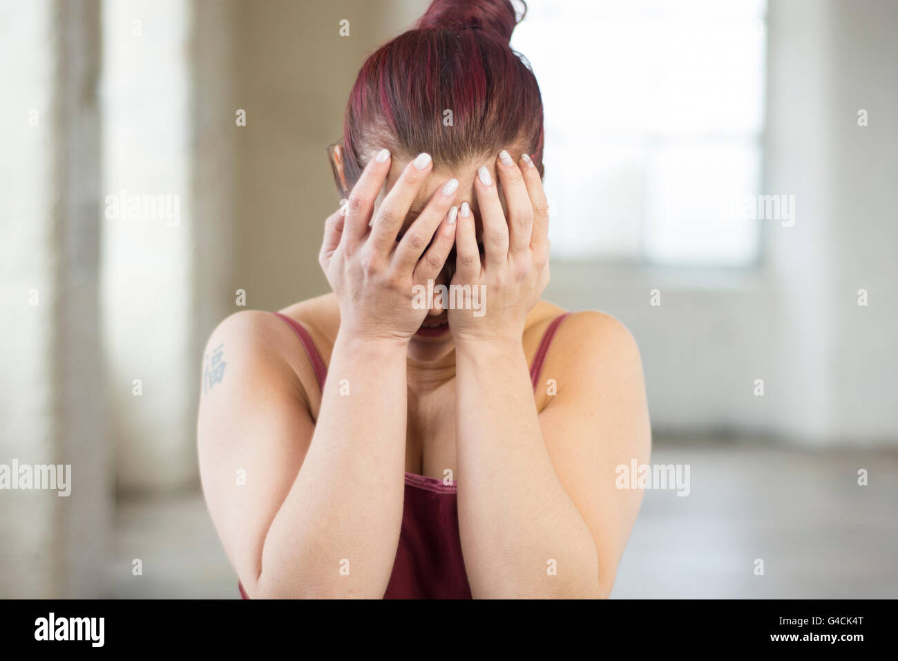 Stressed woman head in hands indoors Stock Photo