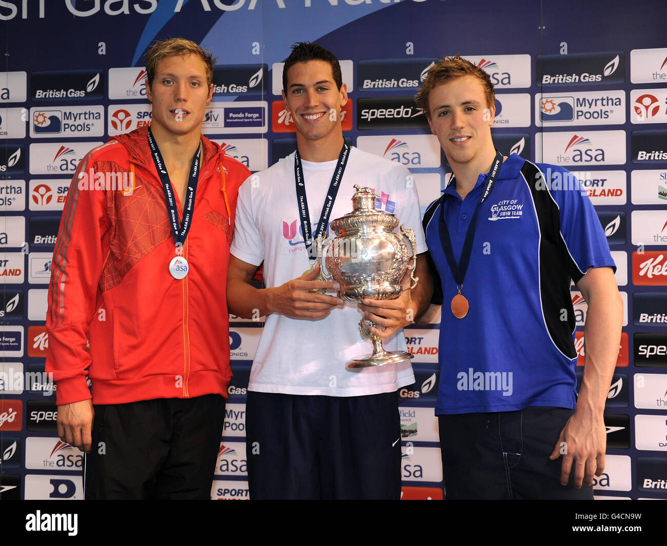 Windsor's Simon Burnett celebrates with his gold medal and trophy for the Men's Open 100m Freestyle alongside silver medalist Grant Turner of Loughborough University (left) and Bronze medalist Robbie Renwick of City of Glasgow (right) during the ASA National Championships at Ponds Forge, Sheffield. Stock Photo