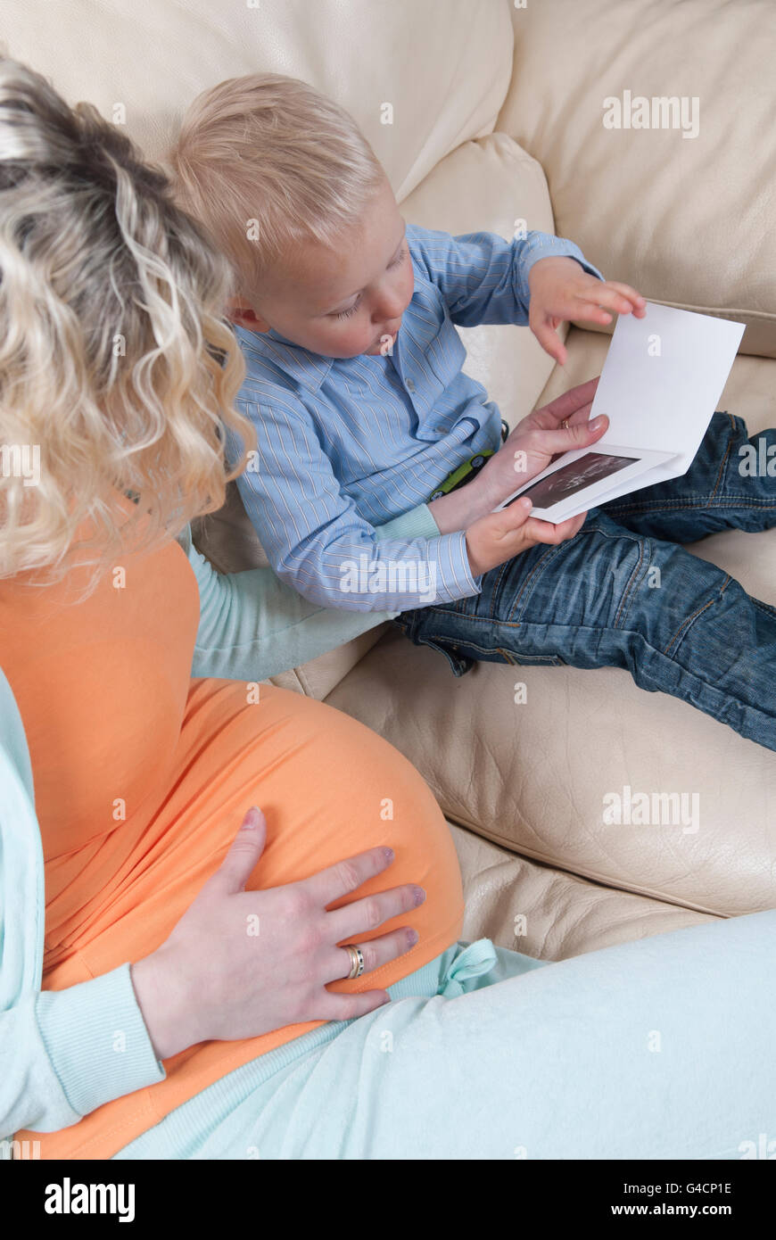 Pregnant woman showing baby scan photo to toddler son Stock Photo