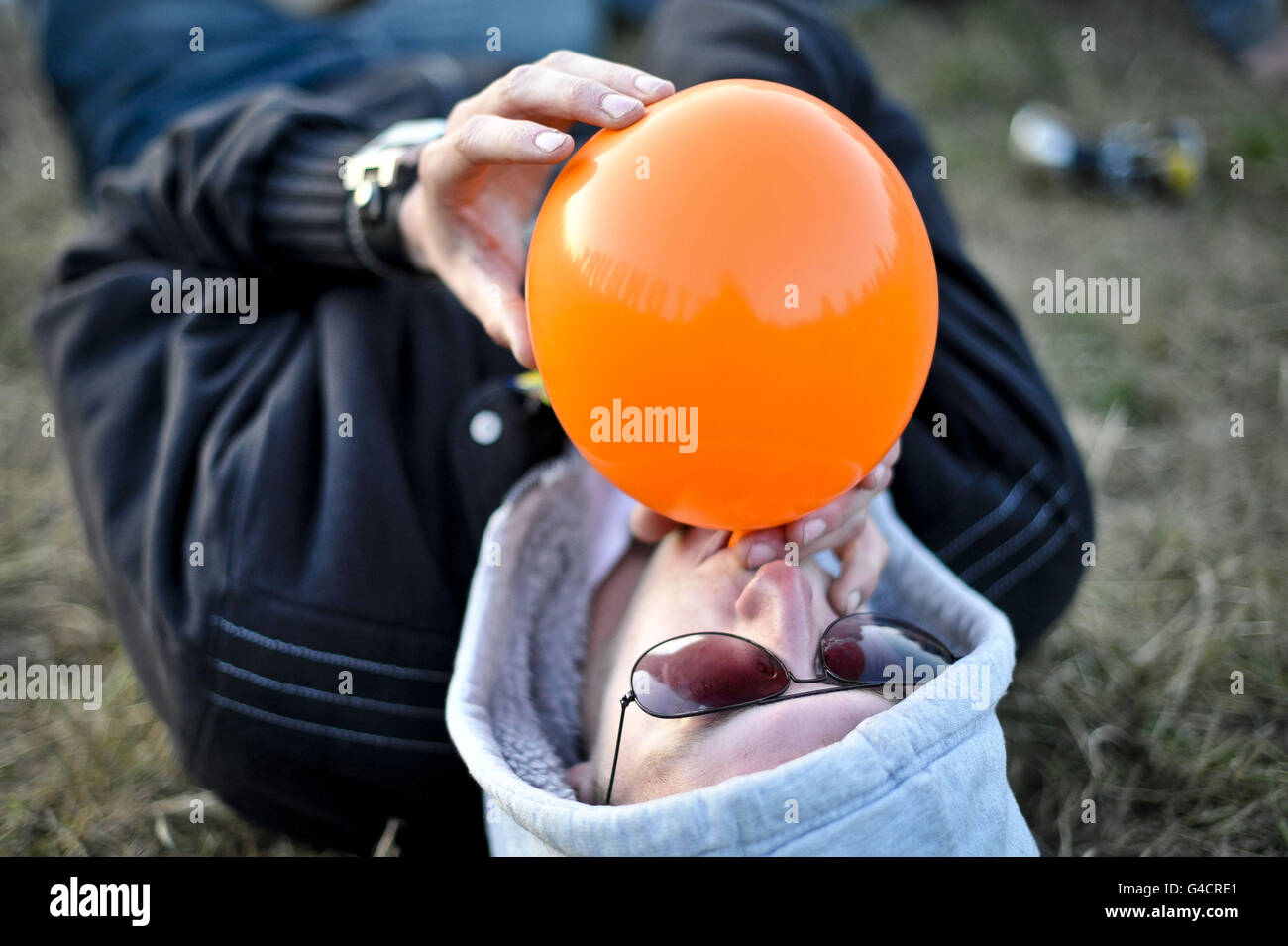 A reveller inhales a nitrous filled balloon after sunset near the Park