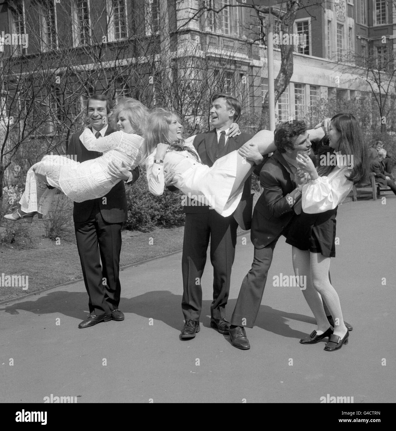 (l-r) Ben Gazzara carrying Jenny Lee-Wright, John Cassavetes carrying Jenny Runacre and Peter Falk with Noelle Kao at the Embankment Gardens, London. They all star in the film 'Husbands'. The men are all American Actors, (Peter Falk becoming famous for playing Lieutenant Columbo) who hand-picked the actresses for the roles of their girlfriends after interviewing 500 candidates. Miss Lee-Wright is the only only English girl. She studies ballet with Ballet Rambert. She has been a Lionel Blair dancer, and it was Lionel's wife Sue who suggested Jenny for the part in 'Husbands'. South African born Stock Photo