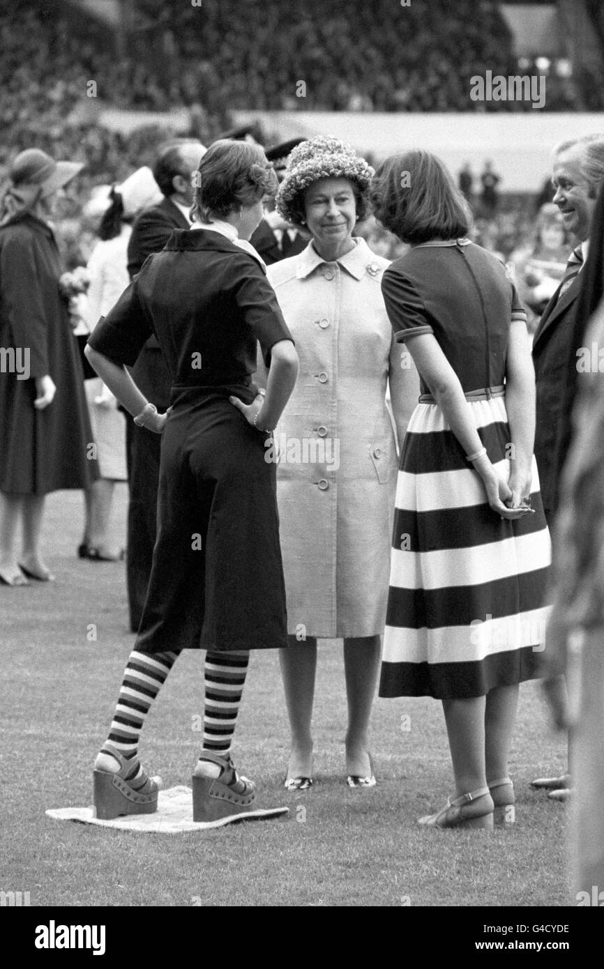 Queen Elizabeth II chats to two teenage girls in trendy fashion gear at Elland Road Football Ground, Leeds. The Queen saw a display staged by 3,500 school children as part of her Silver Jubilee Tour Stock Photo