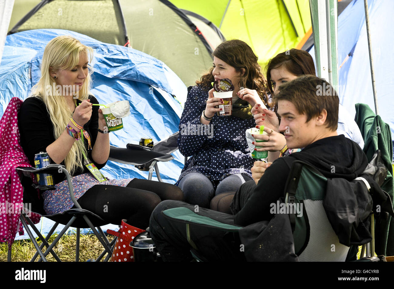 Reveller eat pot noddles outside their tents after arriving at the Glastonbury Festival in Somerset. Stock Photo