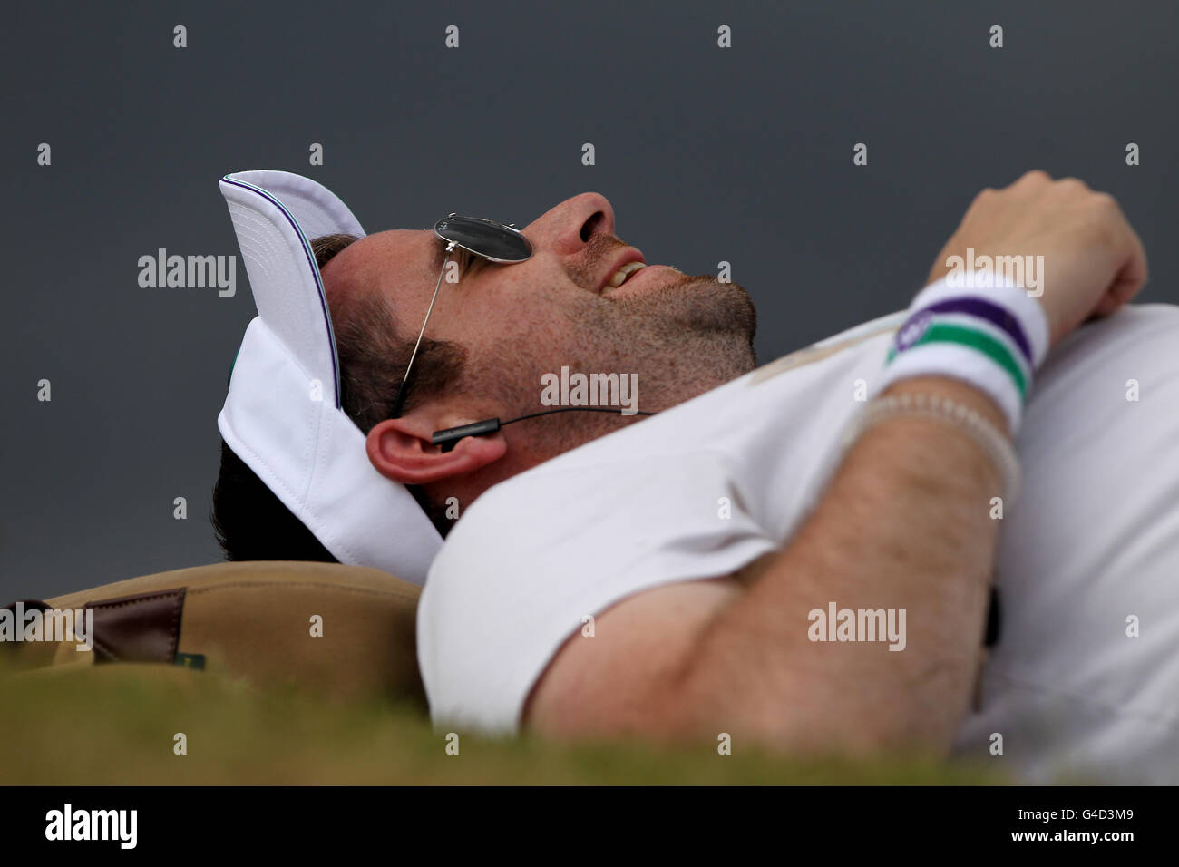 A spectator wearing a tennis outfit lies on his back to watch the