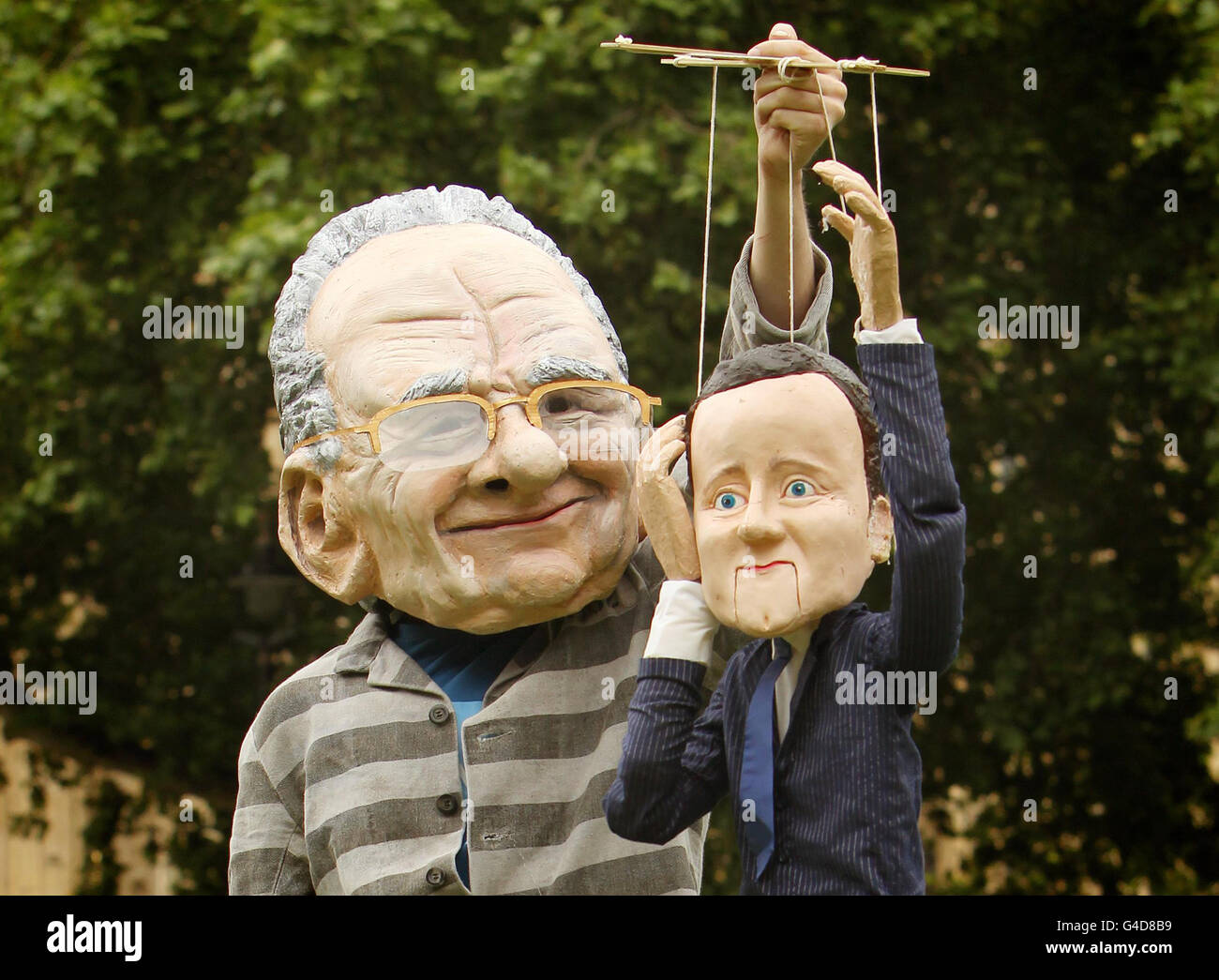 A protestor dressed as Rupert Murdoch holds a puppet of Prime Minister David Cameron, in Westminster, London. Stock Photo