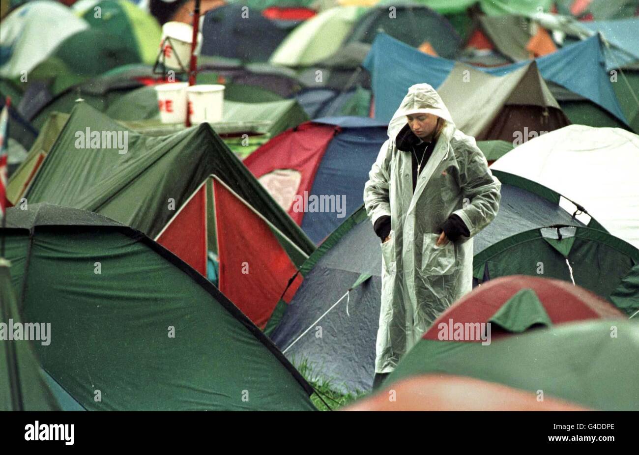 A Glastonbury festival-goer walks through the rain soaked campsite after a night of heavy rain. Stock Photo