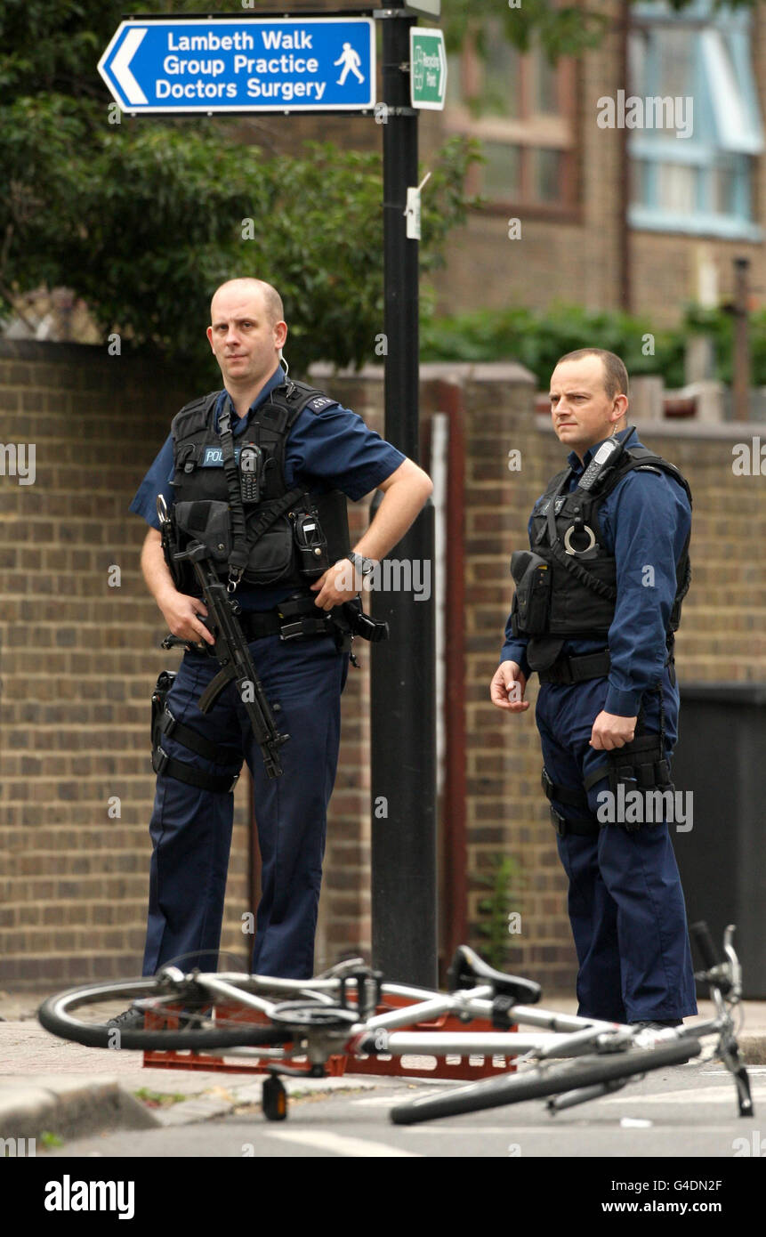 Armed police officers are seen with a bike at the scene of a shooting on Black Prince Lane in Kennington, south London. Stock Photo