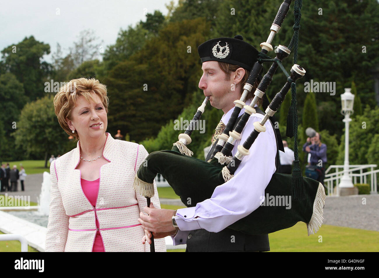 Irish President Mary McAleese listens to Piper Patrick Martin play in the grounds of Aras an Uachtarain during the 12th July Garden Party. Stock Photo