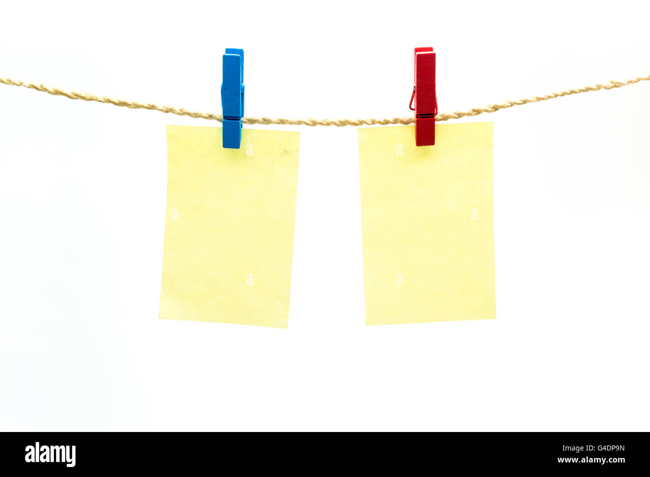 Red and blub clothespins and yellow note paper hanging on rope isolated white background Stock Photo
