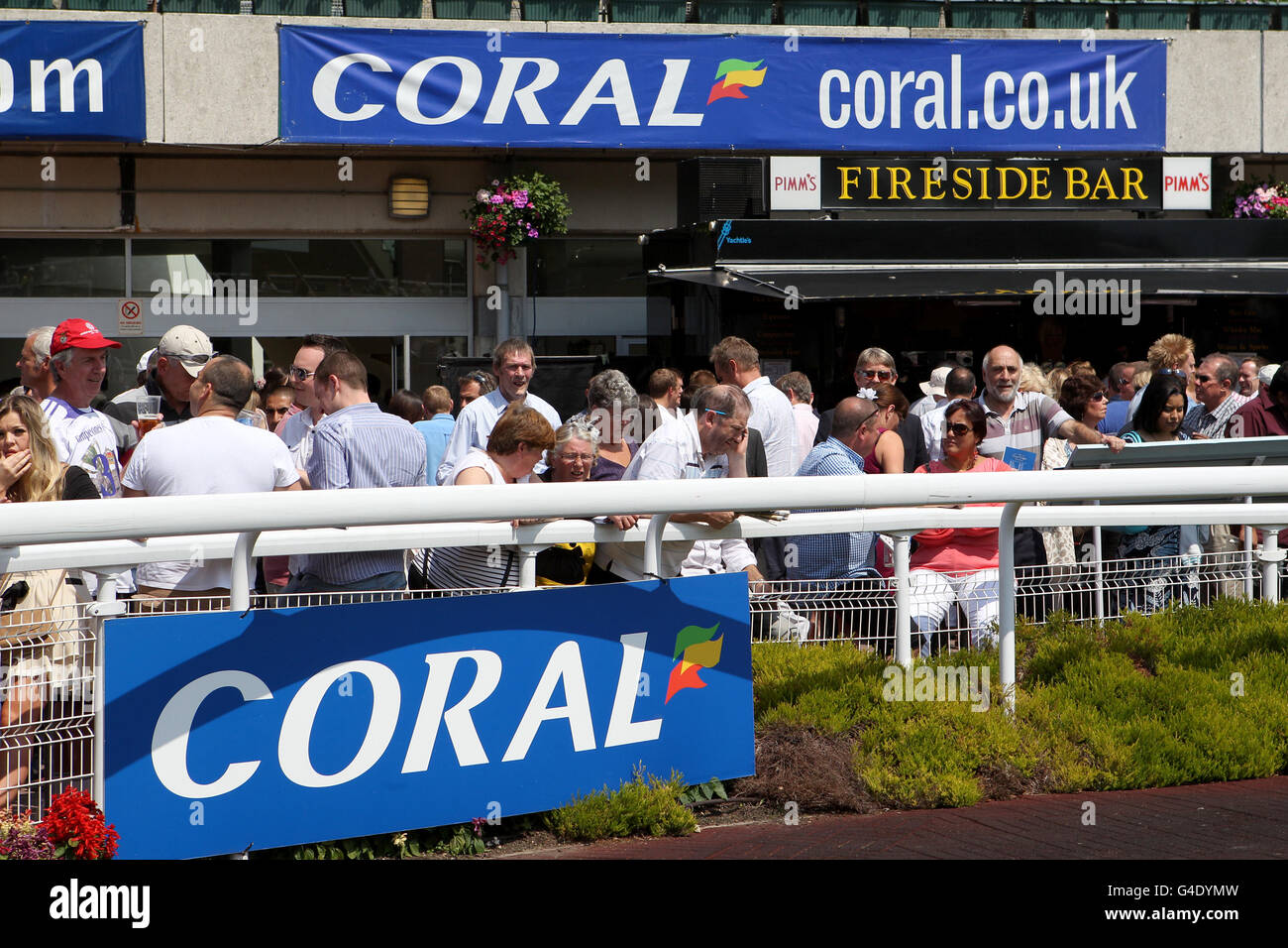 Horse Racing - Coral-Eclipse Day - Sandown Park. Racegoers stand outside of the Fireside Bar outlet Stock Photo