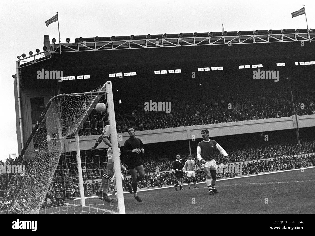 Manchester City goalkeeper Harry Dowd watches the ball soar into the net for Arsenal's first goal, scored by John Radford (not pictured). Also watching is Arsenal's Colin Addison (r). Stock Photo