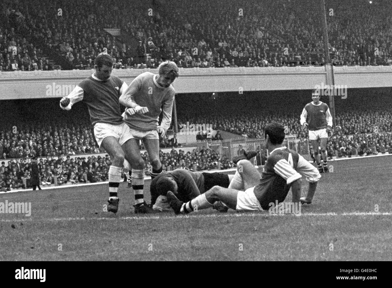 Arsenal goalkeeper Jim Furnell gathers the ball under pressure from teammates Terry Neill (l), Frank McLintock (r) and Manchester City's Colin Bell (c). Stock Photo
