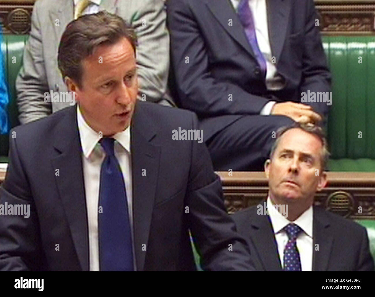 Prime Minister David Cameron reads a statement, as Defence Secretary Liam Fox (right) looks on, as he announces further details of British troop withdrawals from Afghanistan in the House of Commons, London. Stock Photo