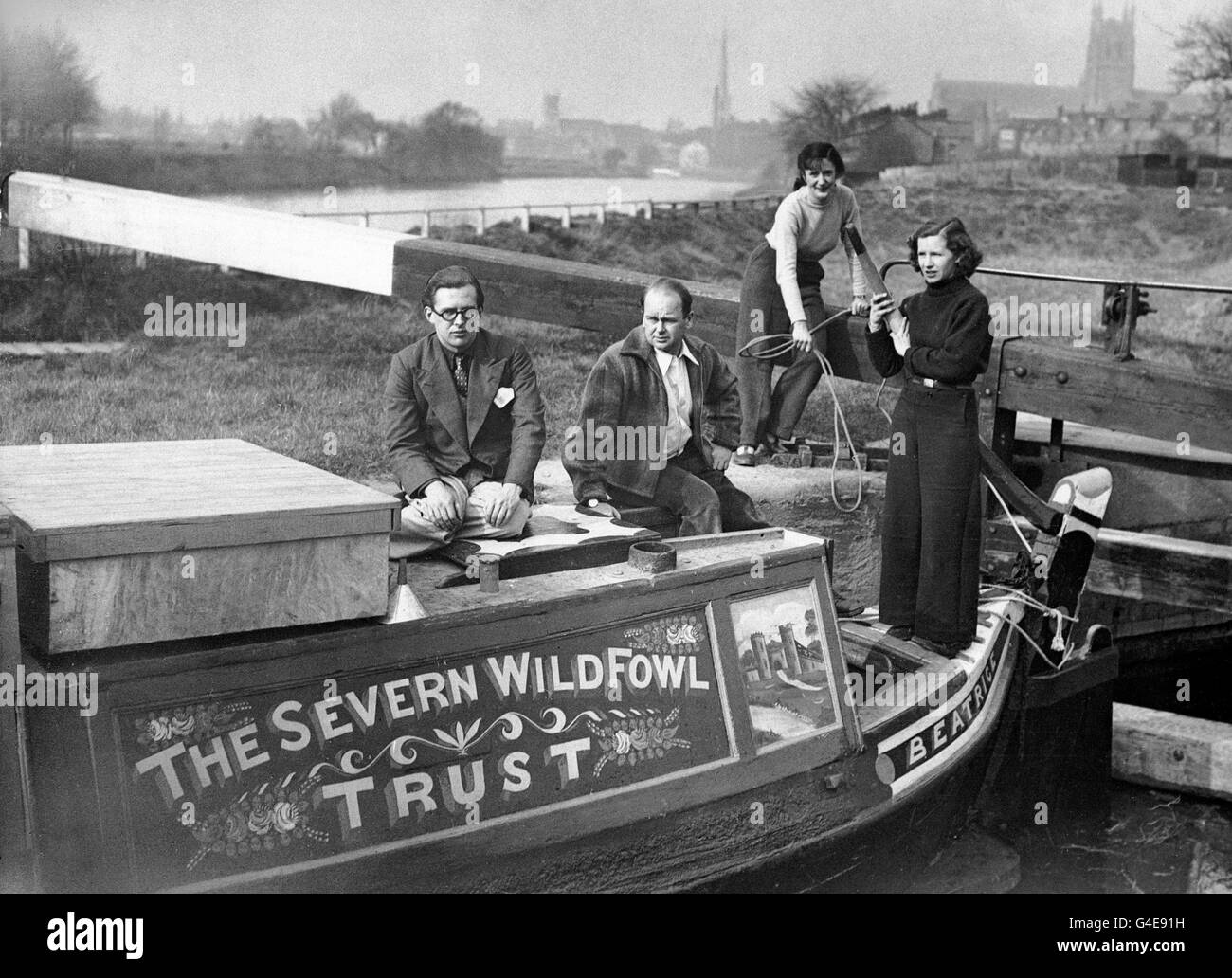 'Beatrice', a former canal boat and now the new floating headquarters of the Severn Wildfowl Trust, moored for a few hours at Diglis Basin, Worcester, on her journey from Birmingham to the lower reaches of the Severn. In command is Peter Scott (centre), naturalist, author and broadcaster. Forming the crew for the trip are (l-r) Robert Aickman, chairman of the Inland Waterways Association, Peter Scott, Mrs Aickman and Miss Talbot-Ponsonby, assistant secretary of the Severn Wildfowl Trust. Stock Photo