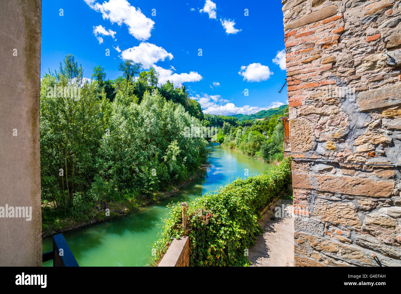 the serenity of a quiet village in the hills of Romagna countryside in Italy, while the cool waters of a placid river bathe the hamlet Stock Photo