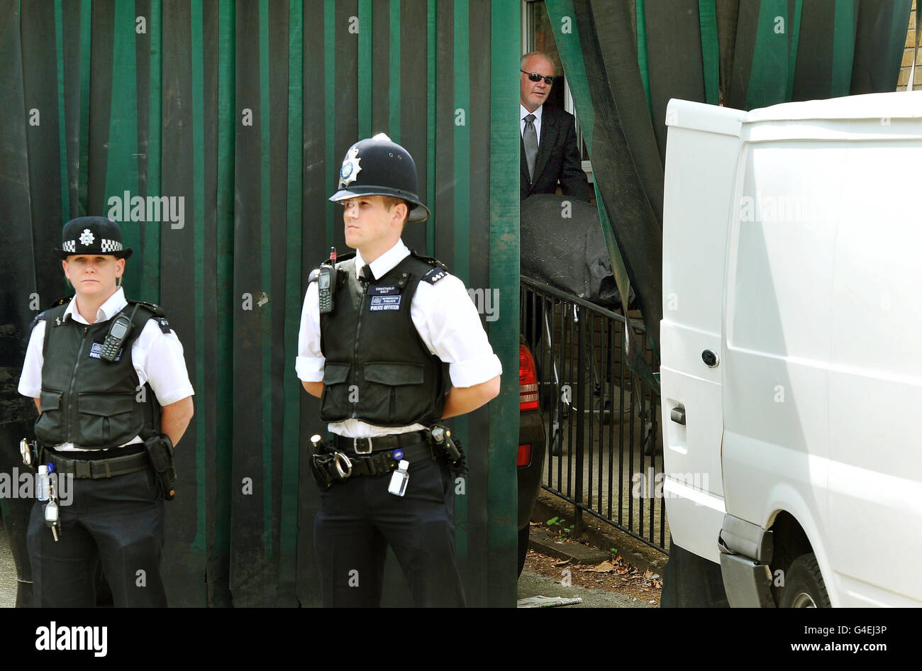 A funeral director (behind screen, right) pushes a wheeled stretcher carrying the body of Amy Winehouse, from the St Pancras Mortuary in north London, following the singer's death on Saturday. Stock Photo