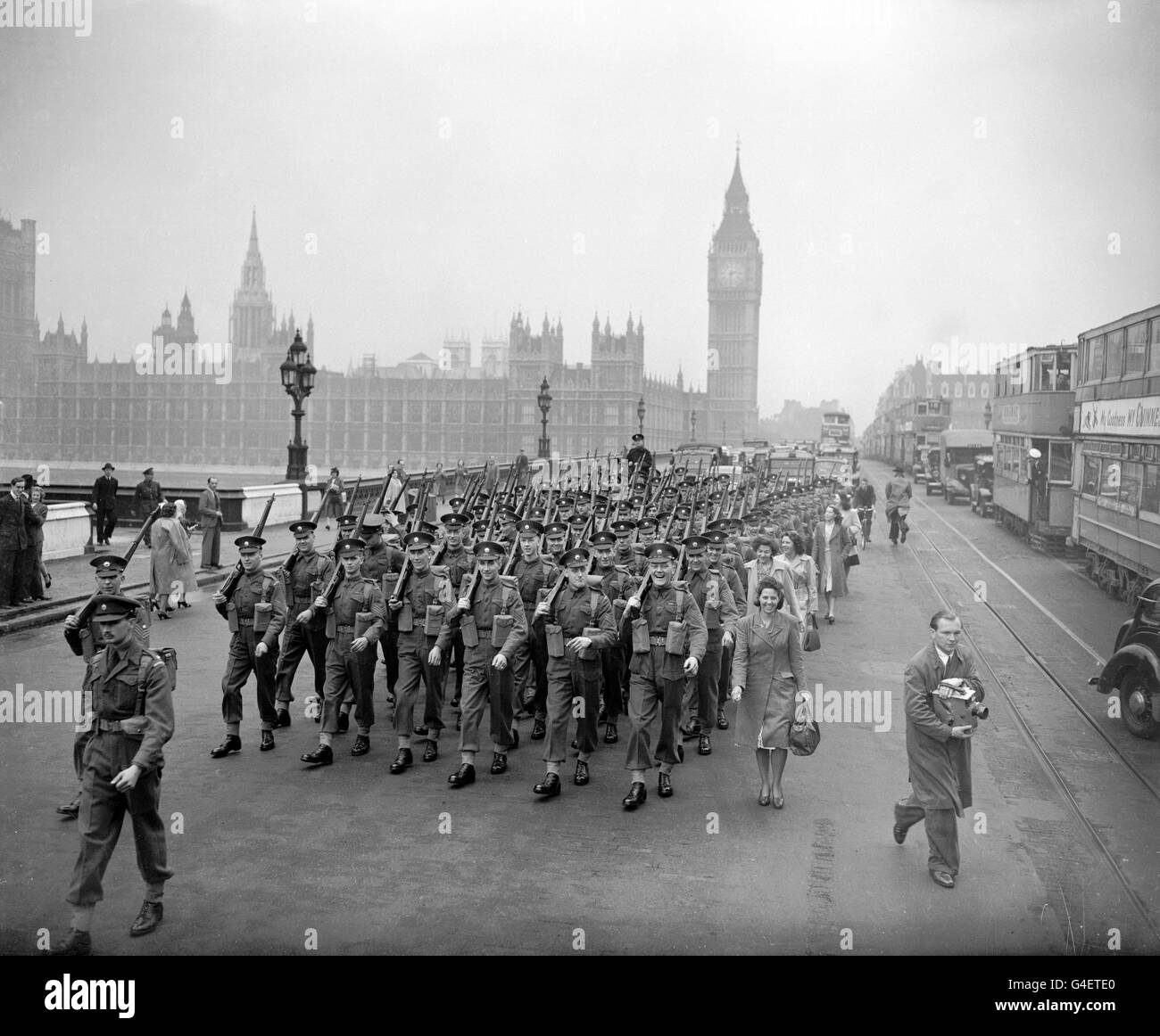 Wives and sweethearts of members of the Brigade of Guards, march with them over Westminster Bridge, on their way to Waterloo Station to catch a train for Southampton en-route for their journey to Malaya to help restore order. The Guards Brigade consists of the 2nd Battalions Coldstream Guards, Scots Guards and an advance party of Grenadiers. Stock Photo