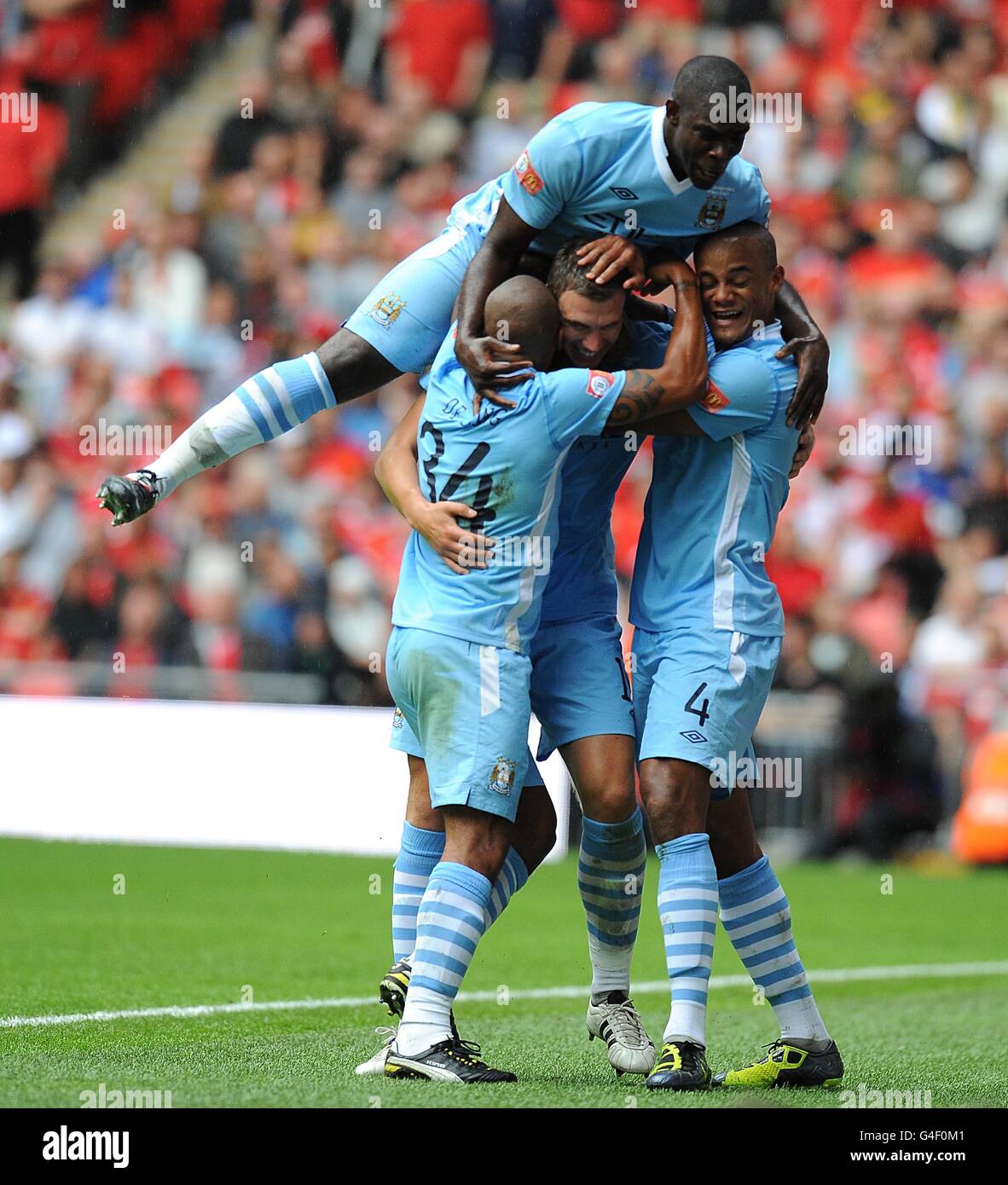 Manchester City's Edin Dzeko celebrates with team mates Mario Balotelli  (top), Vincent Kompany (right) and Nigel de Jong (left) after he scores  their side's second goal of the game Stock Photo -