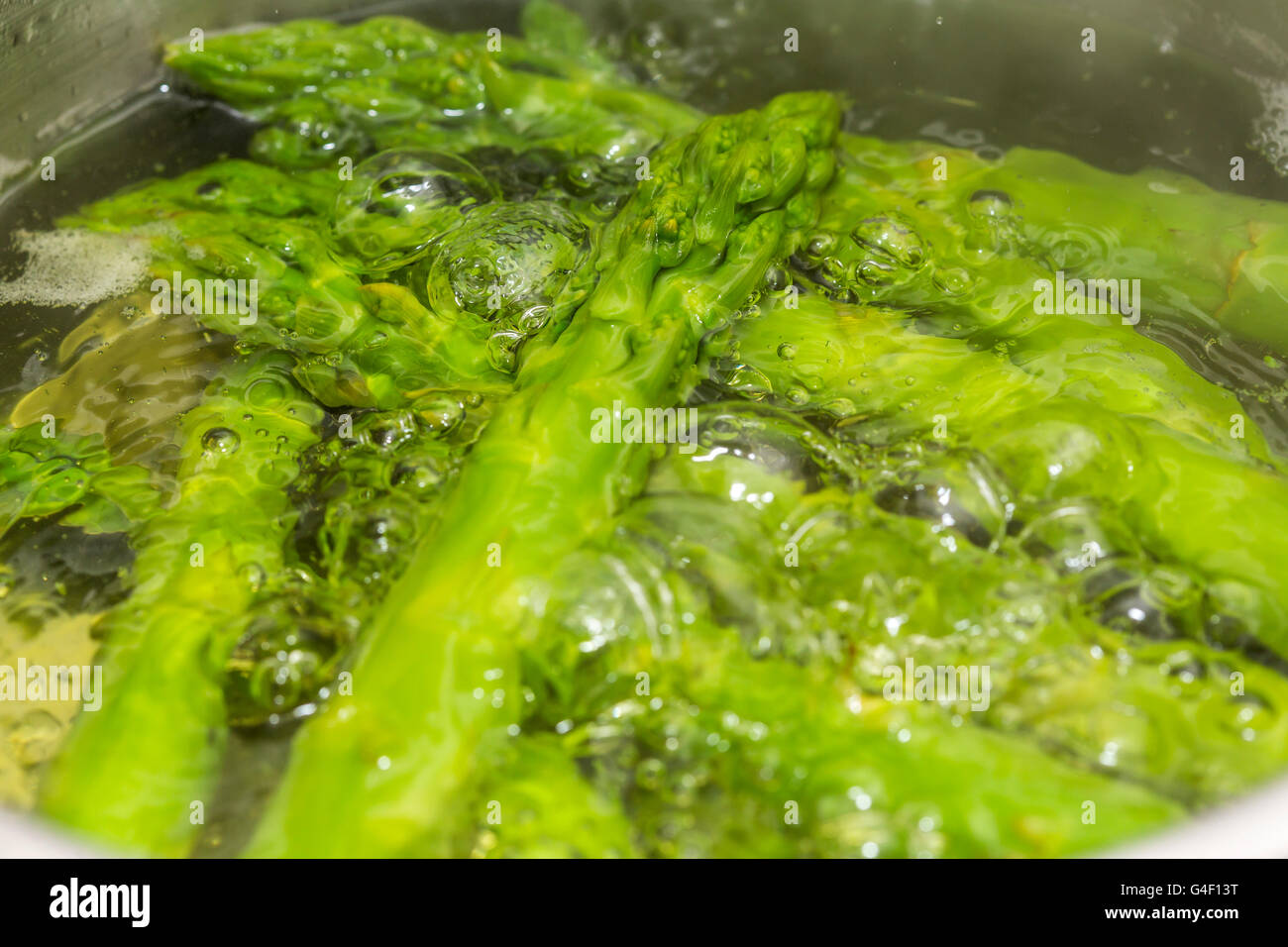 Green asparagus is cooking, boiling, simmering, in a cooking pot, Stock Photo