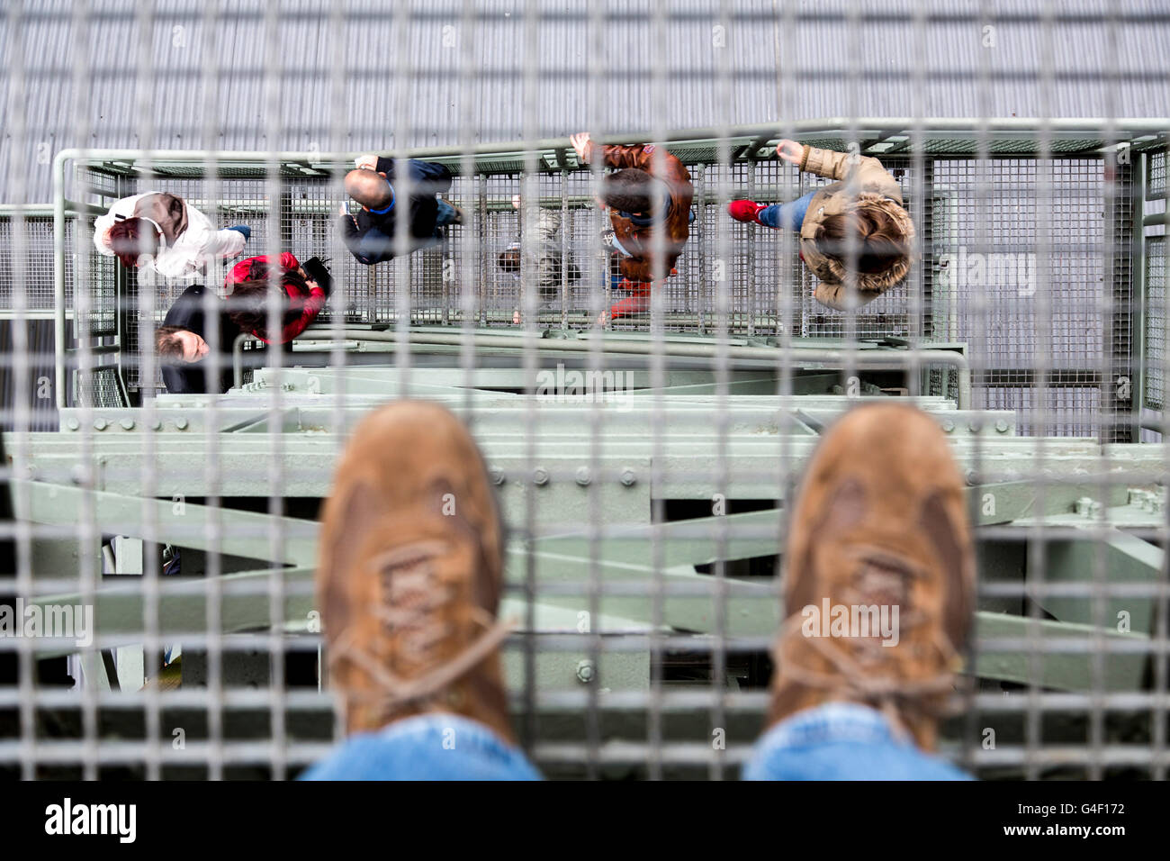 Symbol picture about acrophobia, person stands on the metal grid of a staircase, looking down into the depths, Stock Photo