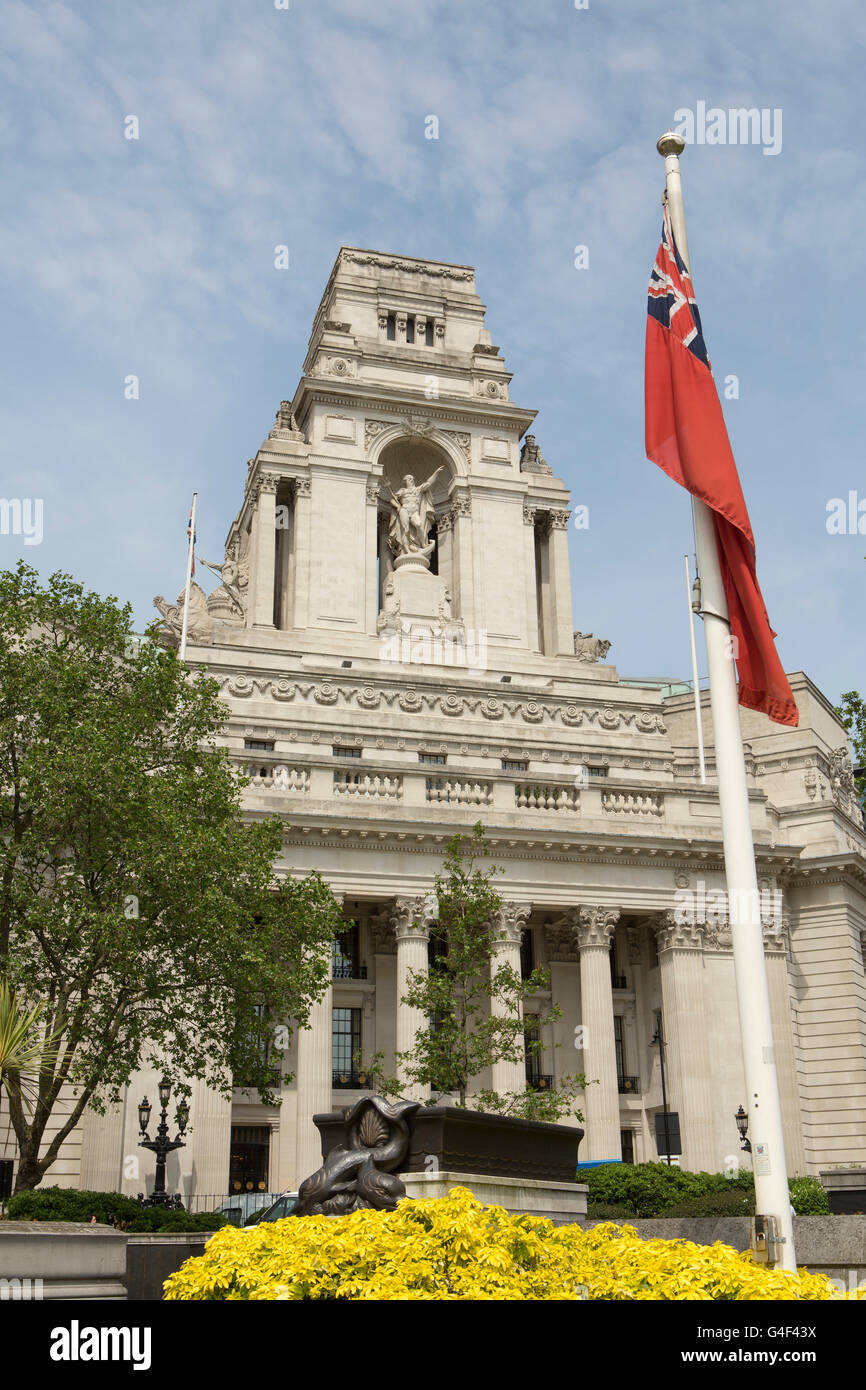 Portrait of the old Port of London Authority Building near the Tower of London. Red ensign and yellow flowers in the foreground. Stock Photo