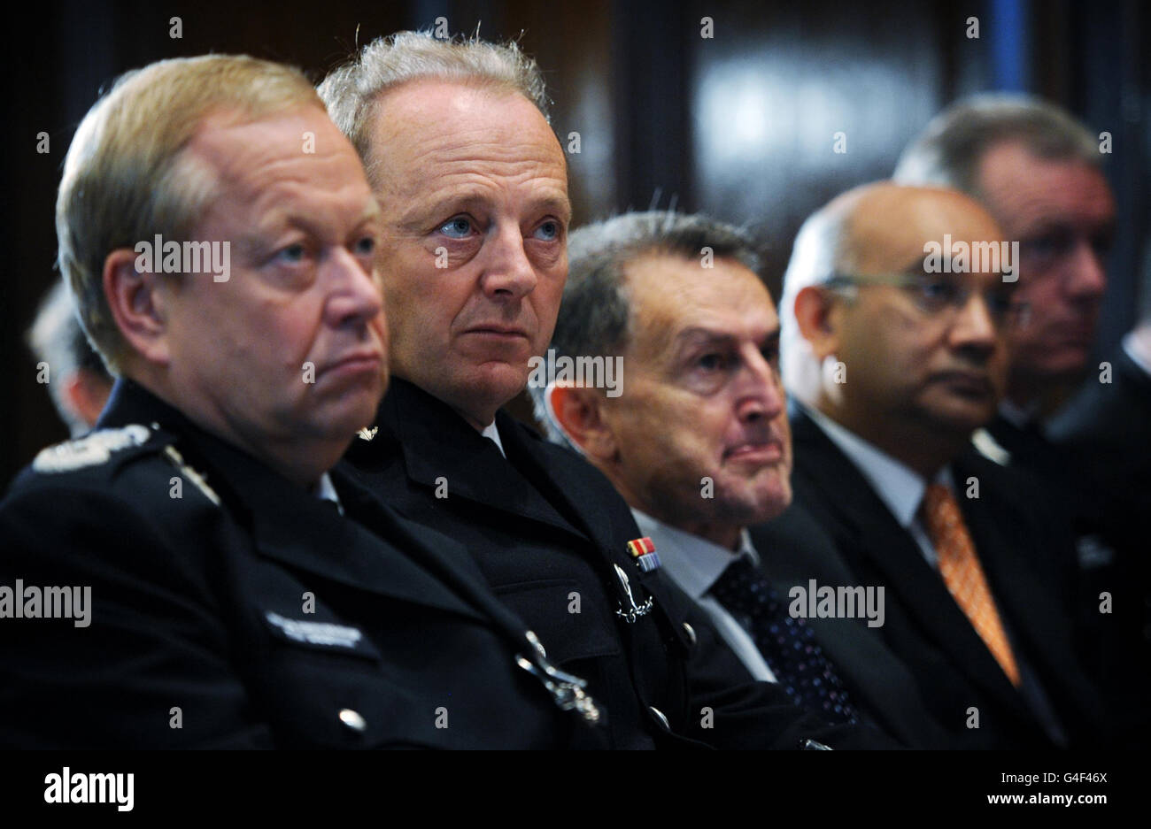 Acting Metropolitan Police Commissioner Tim Godwin (left) and Sir Hugh Orde (second left), President of the Association of Chief Police Officers listen to the Home Secretary Theresa May make a speech on Police reform in central London. Stock Photo