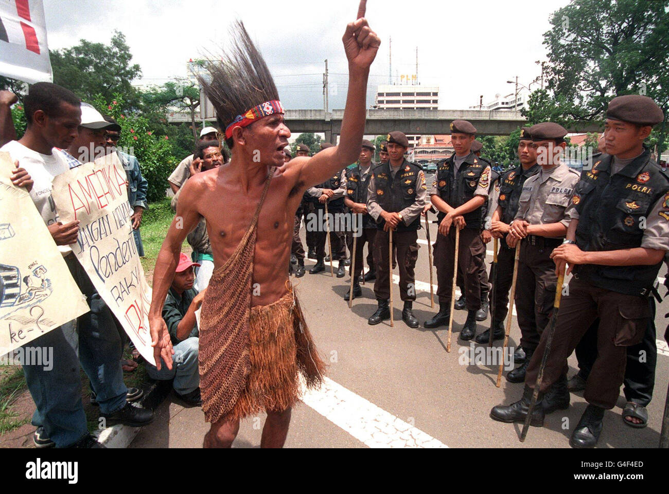 JKT02-19981102-JAKARTA, INDONESIA: An activist from Irian Jaya, dressed in traditional wear, gestures during a demonstration in front of the American embassy, guarded by a cordon of security forces in Jakarta 02 November. The protestors demanded the review of the Freeport contract, including setting an independent probe team and management audit of the company. EPA/AFP PHOTO/KEY Stock Photo