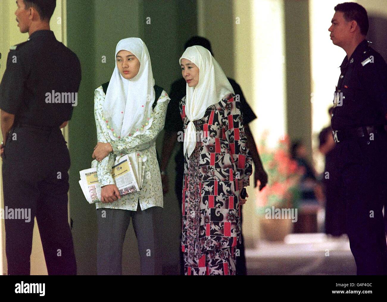 The wife of former premier Anwar Ibrahim, Wan Azizah Wan Ismail (second from R) and daughter Nurul Izzah wait at the corridor of the court house 03 November in Kuala Lumpur. Anwar was set to enter its second day with the United States leading pressure for international observers to be given better access to the proceedings. AFP PHOTO/CHAN LOOI TAT Stock Photo