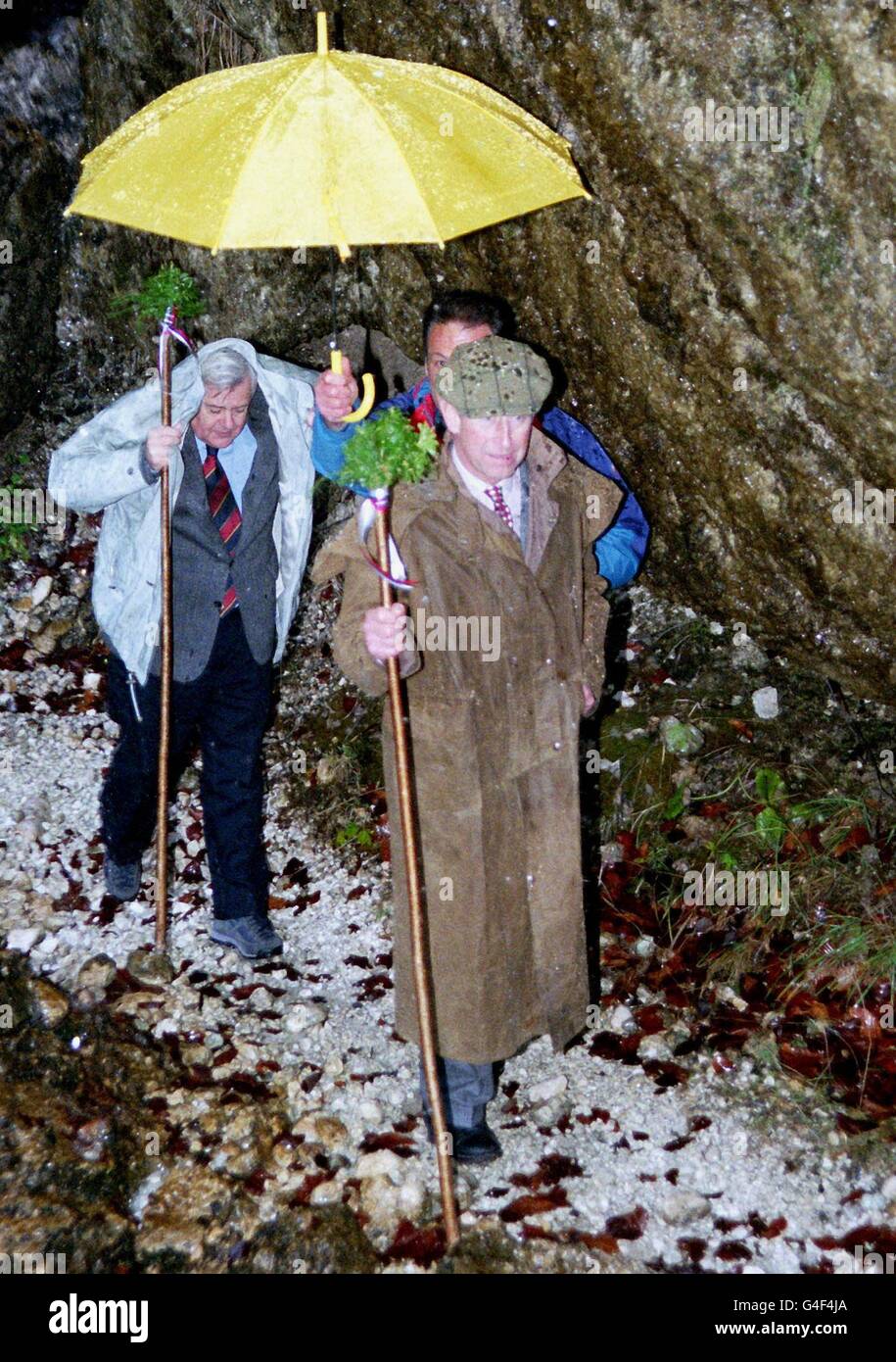 LJU12-19981102-PERICNIK, SLOVENIA: Slovenian President Milan Kucan (L) protects himself against the pouring water while HRH The Prince of Wales (R) is protected with an umbrella as they walk under the Pericnik waterfalls, 02 November 1998, during the Prince's visit here on the first day of his two-days offical visit to Slovenia. PA NEWS PHOTO Stock Photo
