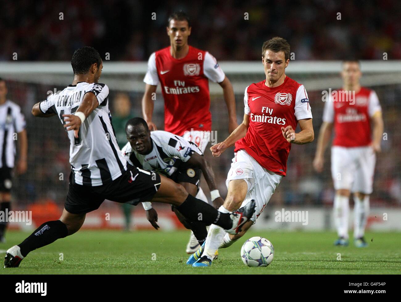 Soccer - UEFA Champions League - Play Offs - First Leg - Arsenal v Udinese - Emirates Stadium. Arsenal's Aaron Ramsey (2nd right) takes on Udinese's Mehdi Benatia in a battle for the ball Stock Photo