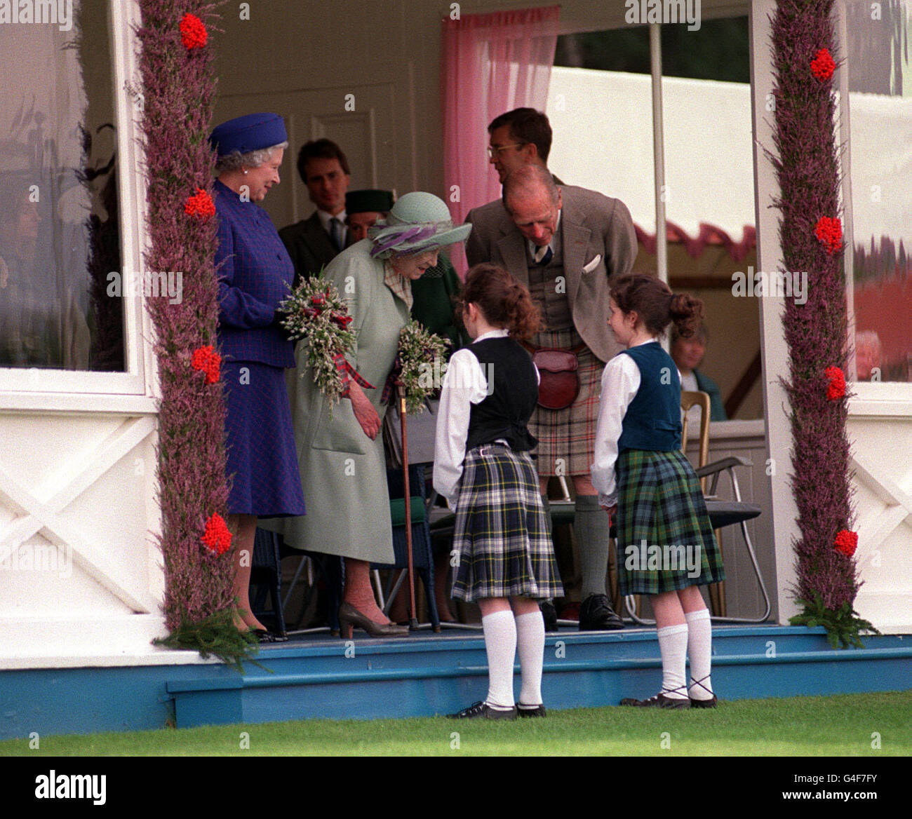 PA NEWS PHOTO 5/9/98 THE QUEEN AND QUEEN MOTHER RECEIVE FLOWERS FROM TWO GIRLS WHILE THE DUKE OF EDINBURGH LOOKS ON AT THE HIGHLAND GAMES AT BRAEMAR CLOSE TO THEIR HOLIDAY HOME OF BALMORAL CASTLE. Stock Photo
