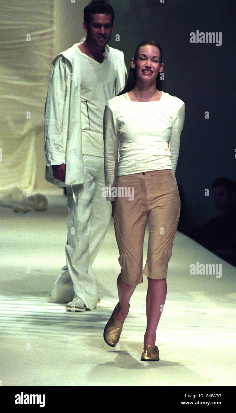 His and Hers, a male and female model wear outfits from the Red or Dead Summer Collection during London Fashion Week. She wears a white T-shirt style with three quarter length camel-coloured trousers and he wears white linen trousers and jacket with a white v-neck T-shirt. Stock Photo