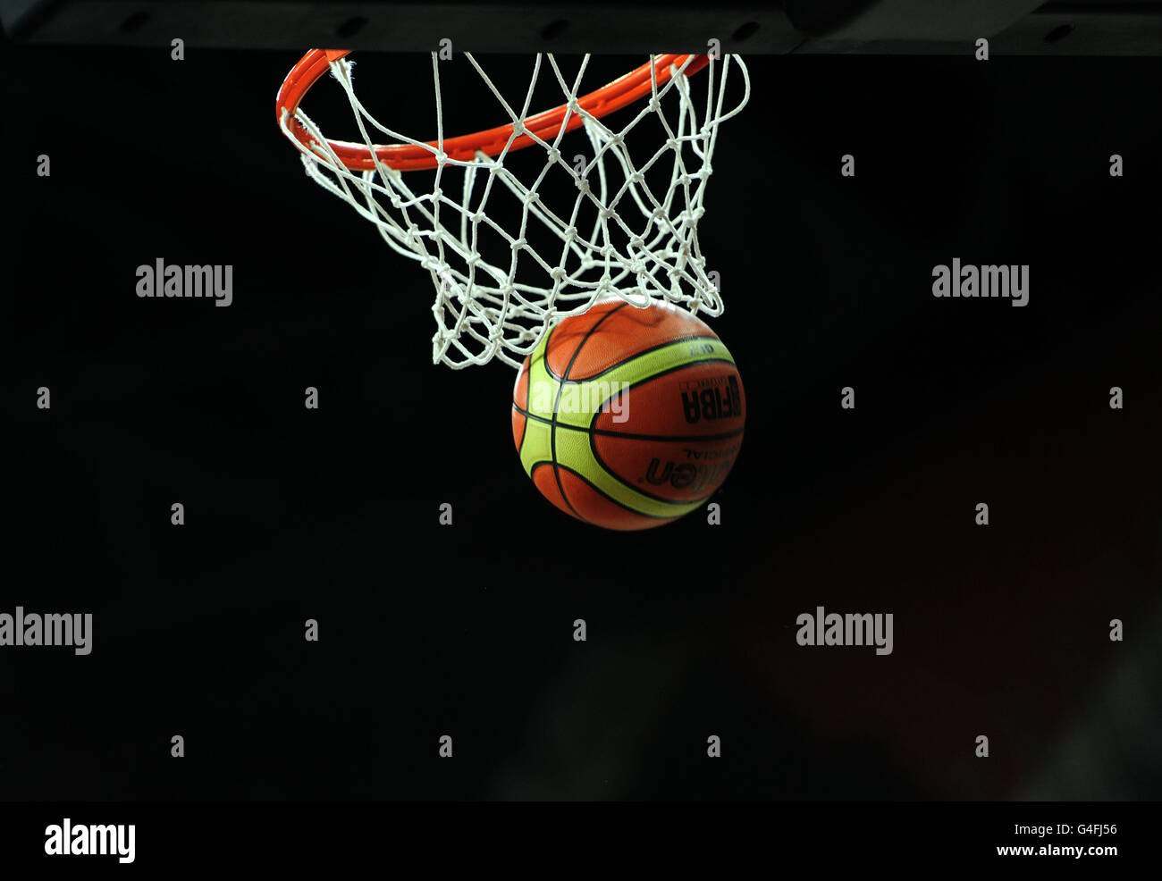 A basketball goes through the hoop during the match between Great Britain and Australia during London Invitational International at the Basketball Arena, in the Olympic Park, London. Stock Photo