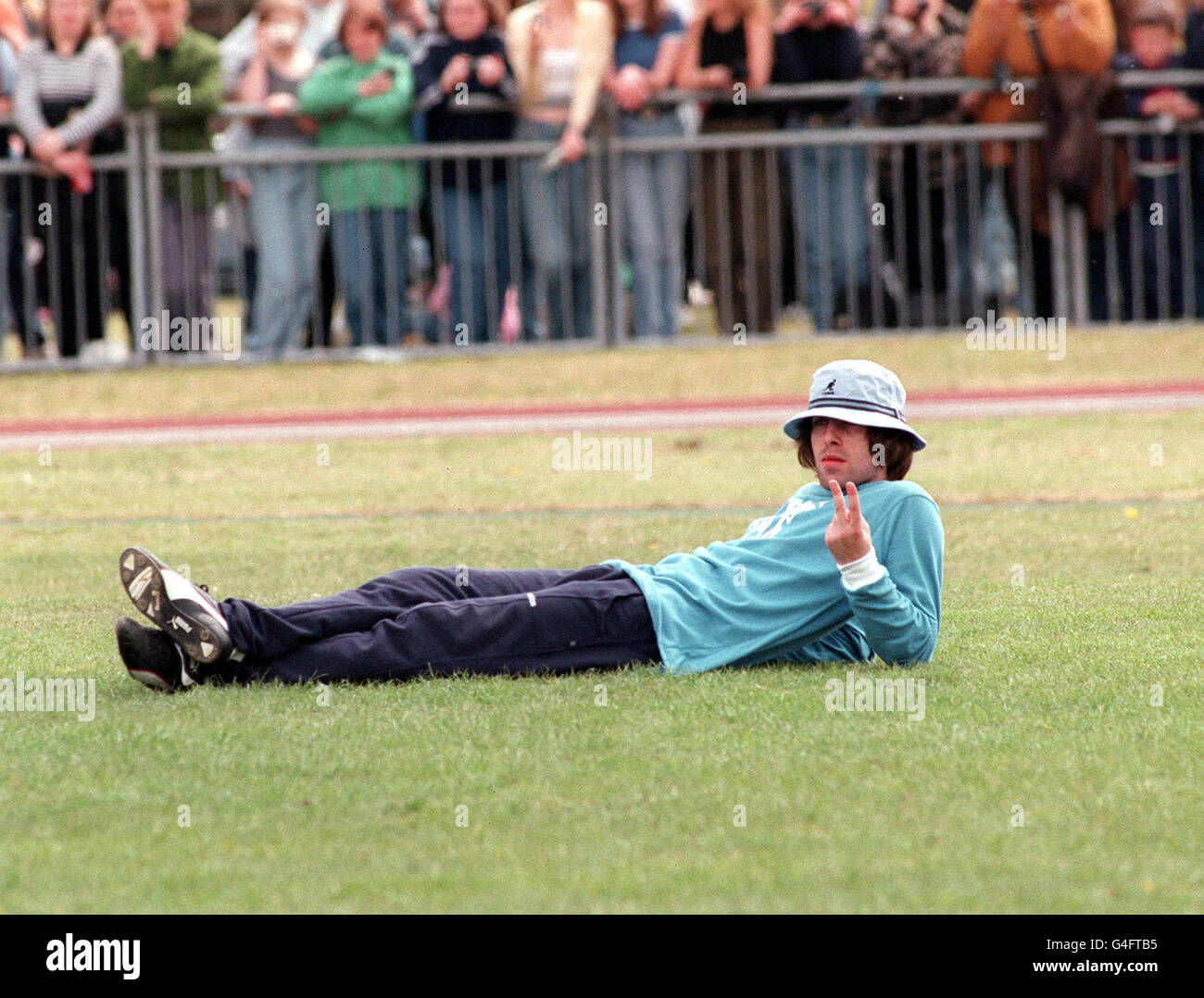 LIAM GALLAGHER OF "OASIS" TAKES TIME OUT TO MAKE HIS USUAL IMMATURE GESTURE TO THE MEDIA DURING THE SECOND MUSIC INDUSTRY "SOCCER SIX" FOOTBALL TOURNAMENT AT MILE END STADIUM IN AID OF THE NORDOFF ROBBINS CHARITY EVENT FOR MUSIC THERAPY CENTRE Stock Photo