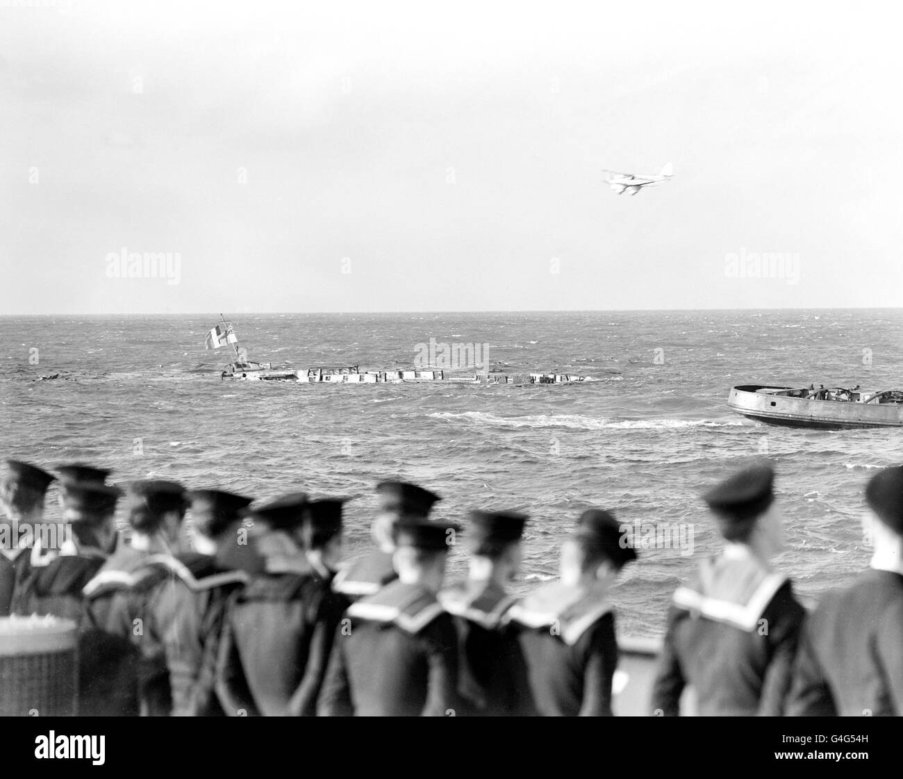 The 'Implacable' is sunk in the English Channel. The 156 year old man-of-war was seized by the British from the French Navy during the Battle of Trafalgar. The ship is to be sunk after wooden timbers of the craft had rotted beyond repair. Sailors lining the HMS Boxer look on as an aircraft flies over the scene Stock Photo