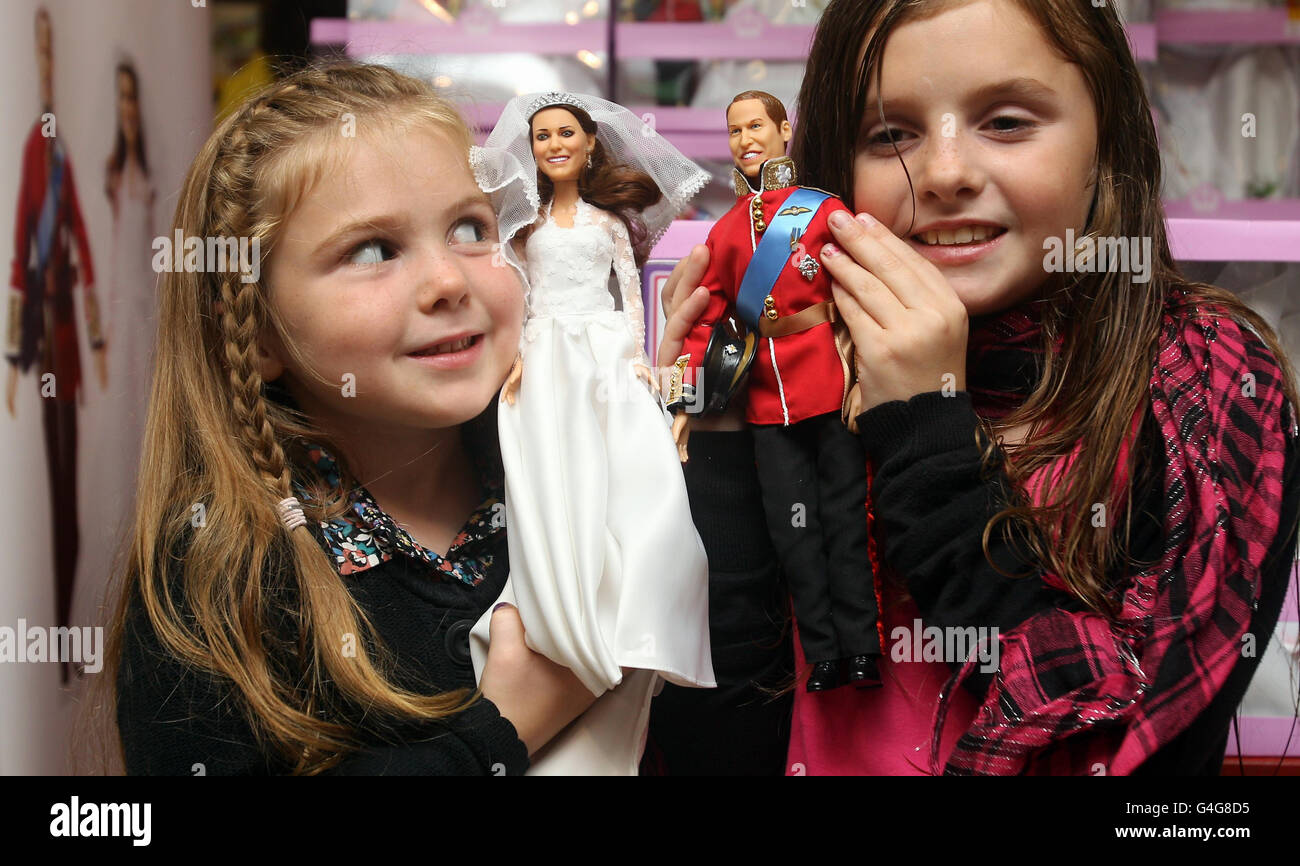 Daisy, 5, and Millie Robinson, 9, from Suffolk with the new Duke and Duchess of Cambridge dolls, called Prince William and Princess Catherine, during the launch at Hamleys in central London. Stock Photo