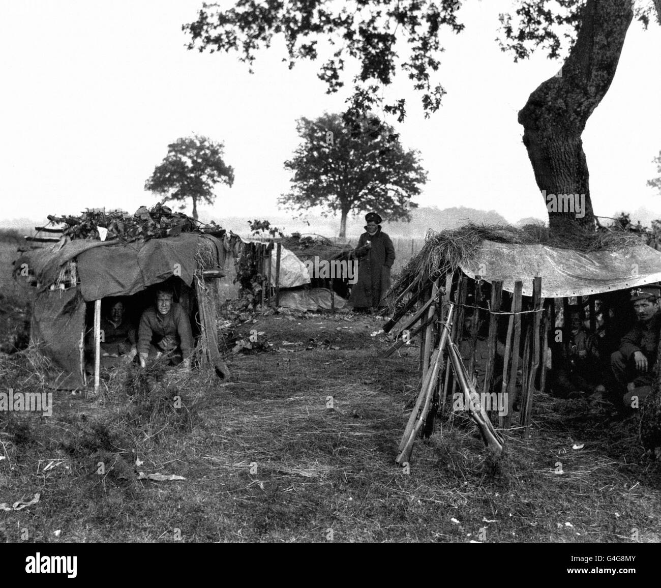 British soldiers take cover in their rudimentary bivouacs, constructed from tarpaulins and fencing, in the French countryside. Stock Photo